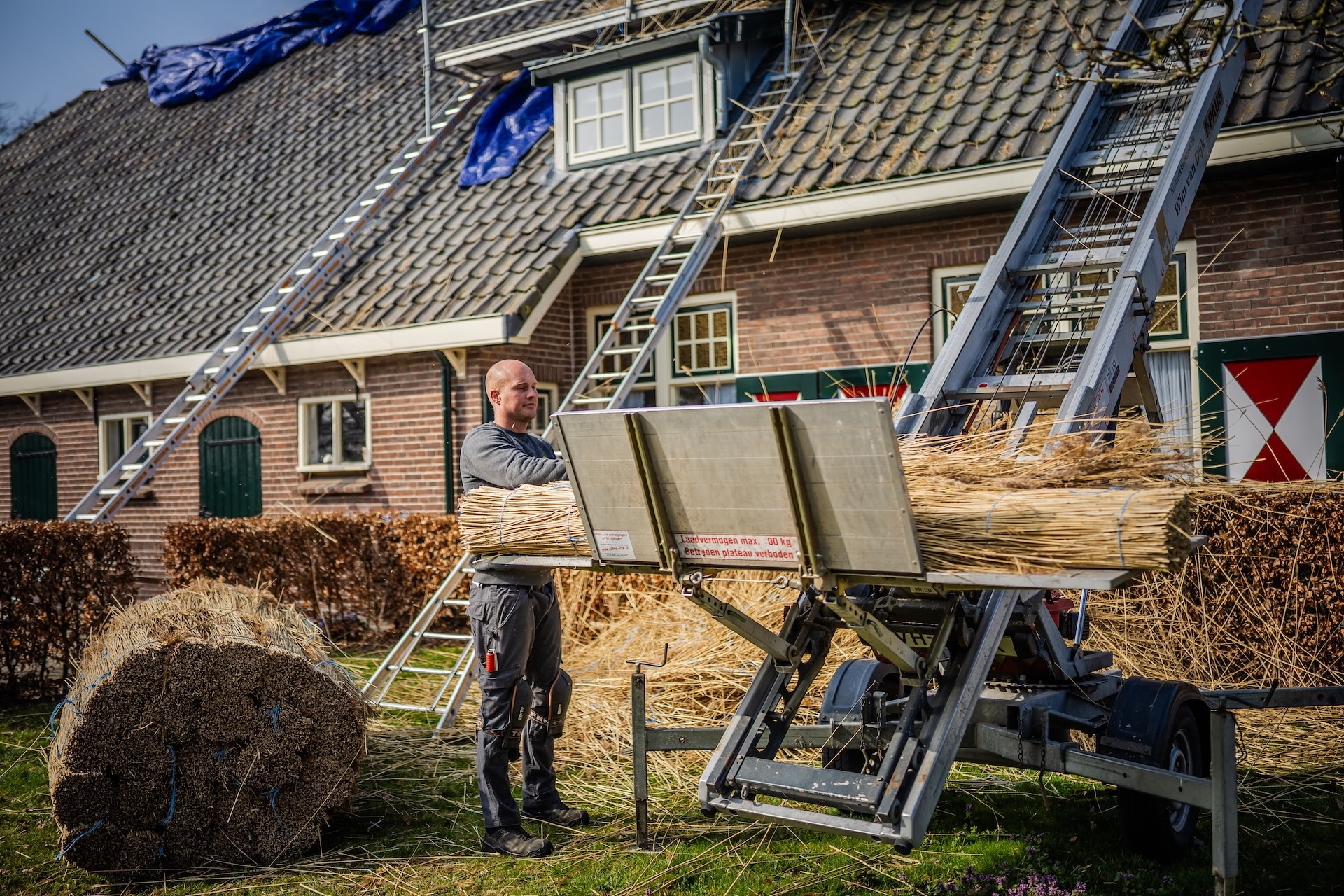 Rietdekker van Rietdekkersbedrijf van Dijk werkend aan de vervanging van dakpannen met een rieten dak