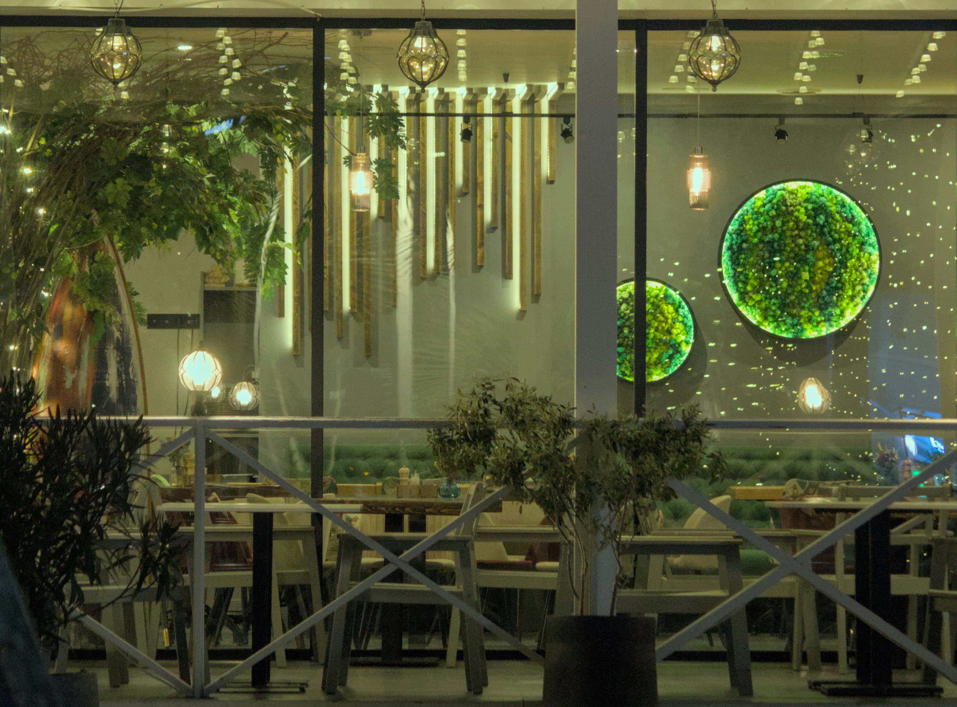 Modern restaurant interior with green wall art and warm lights.