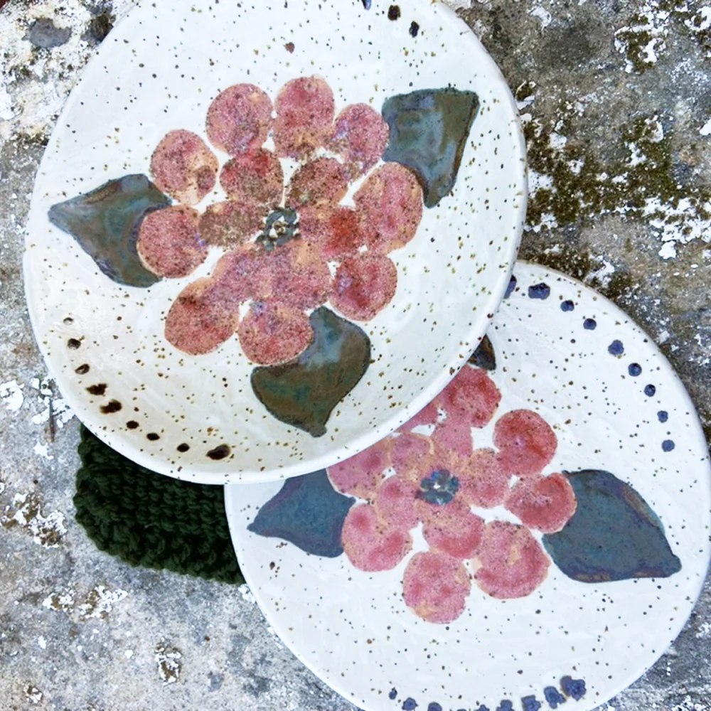 Platos de cerámica artesanal con esmaltes y decoraciones florales creados durante el proceso cerámico.