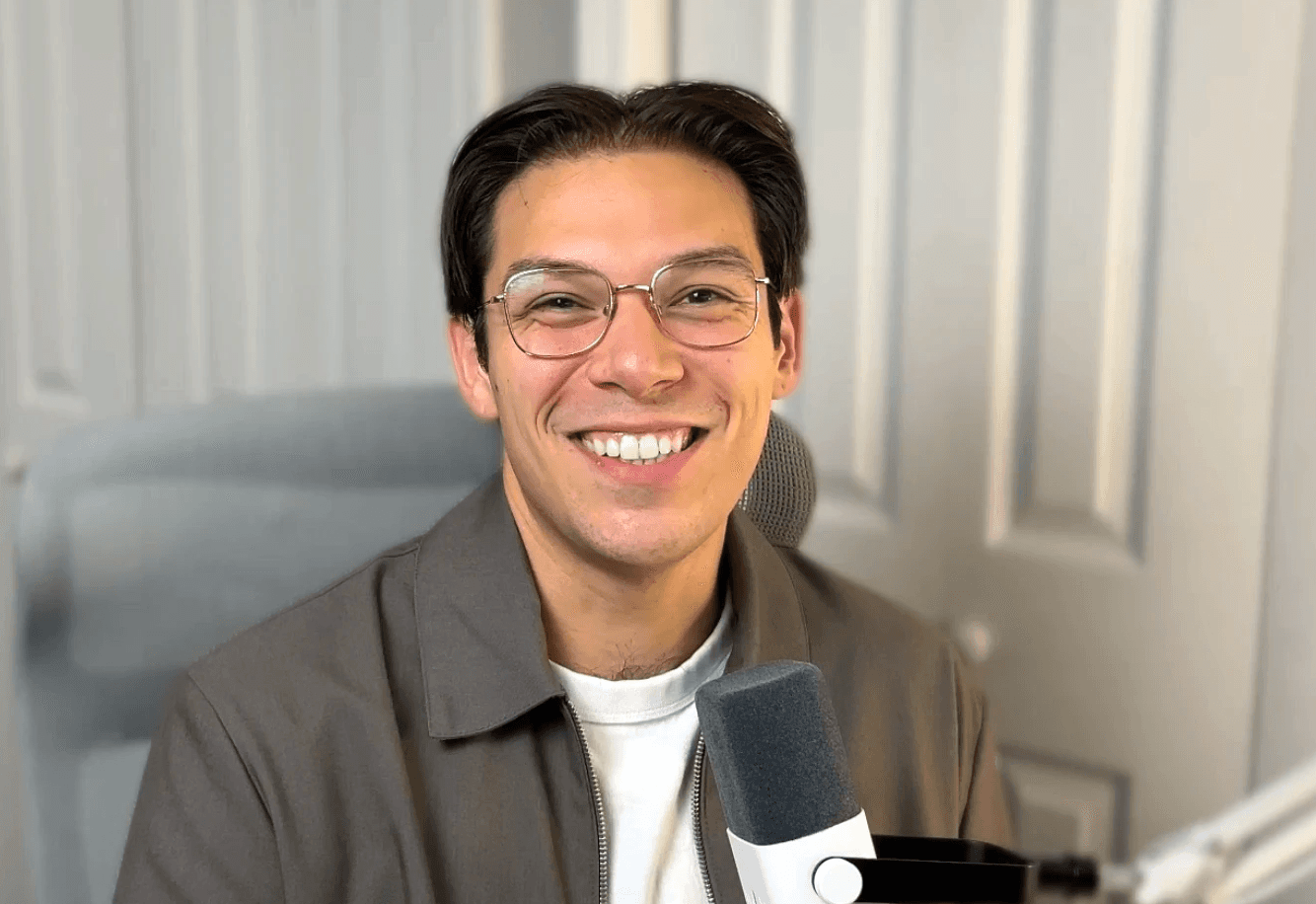 A thoughtful young person with dark hair gazes to the side, captured in soft black and white lighting.