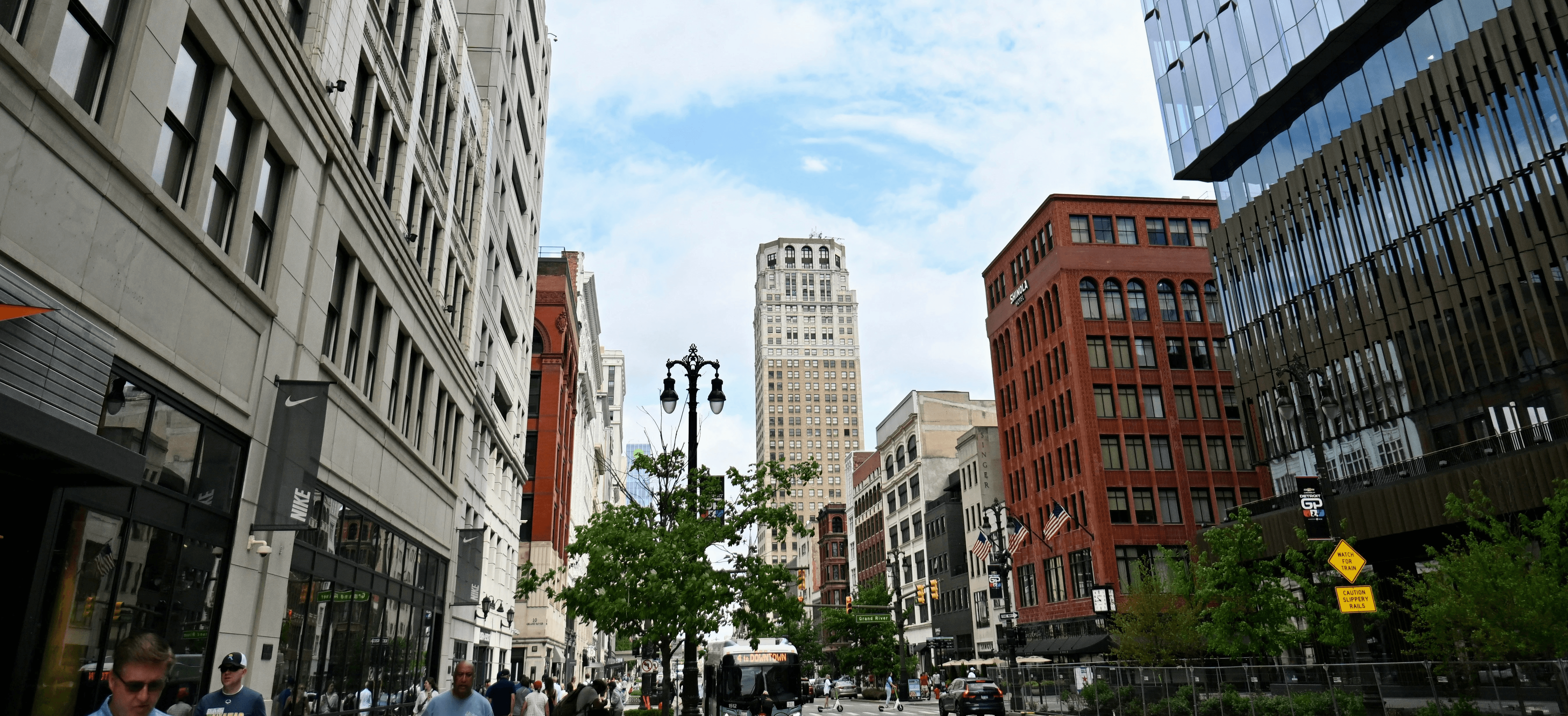 a group of people walking down a street next to tall buildings