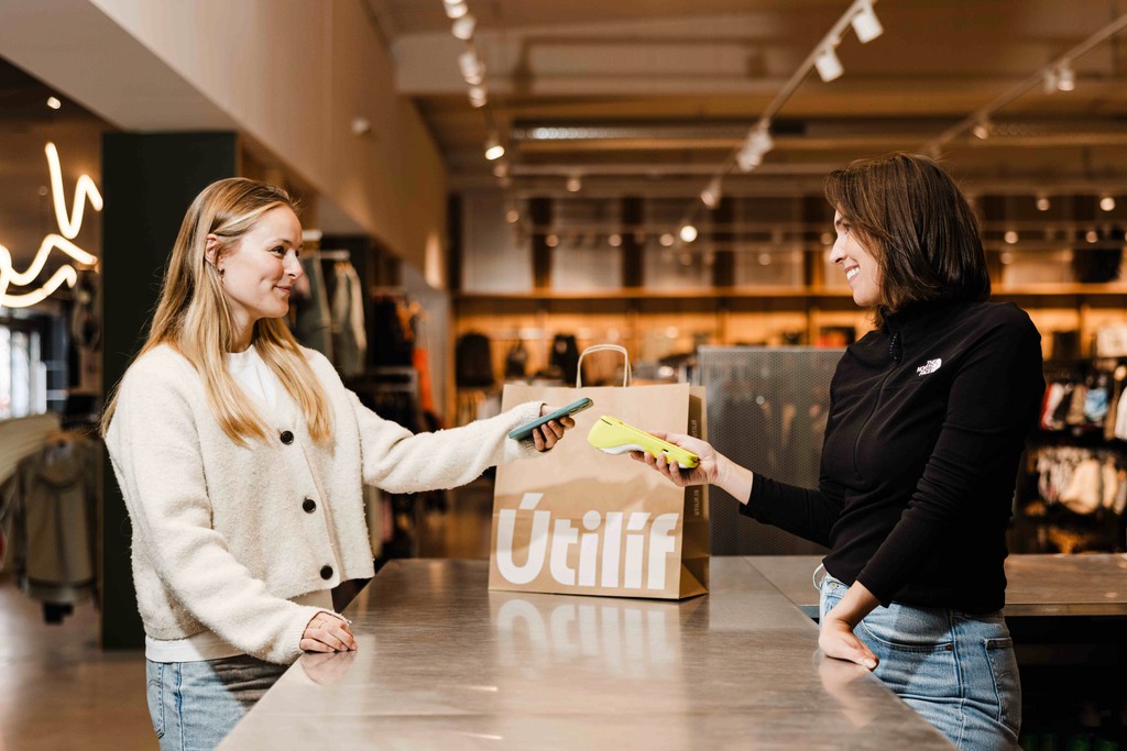 two women, a customer and a business owner, use a Teya card machine to complete a purchase in a clothing shop