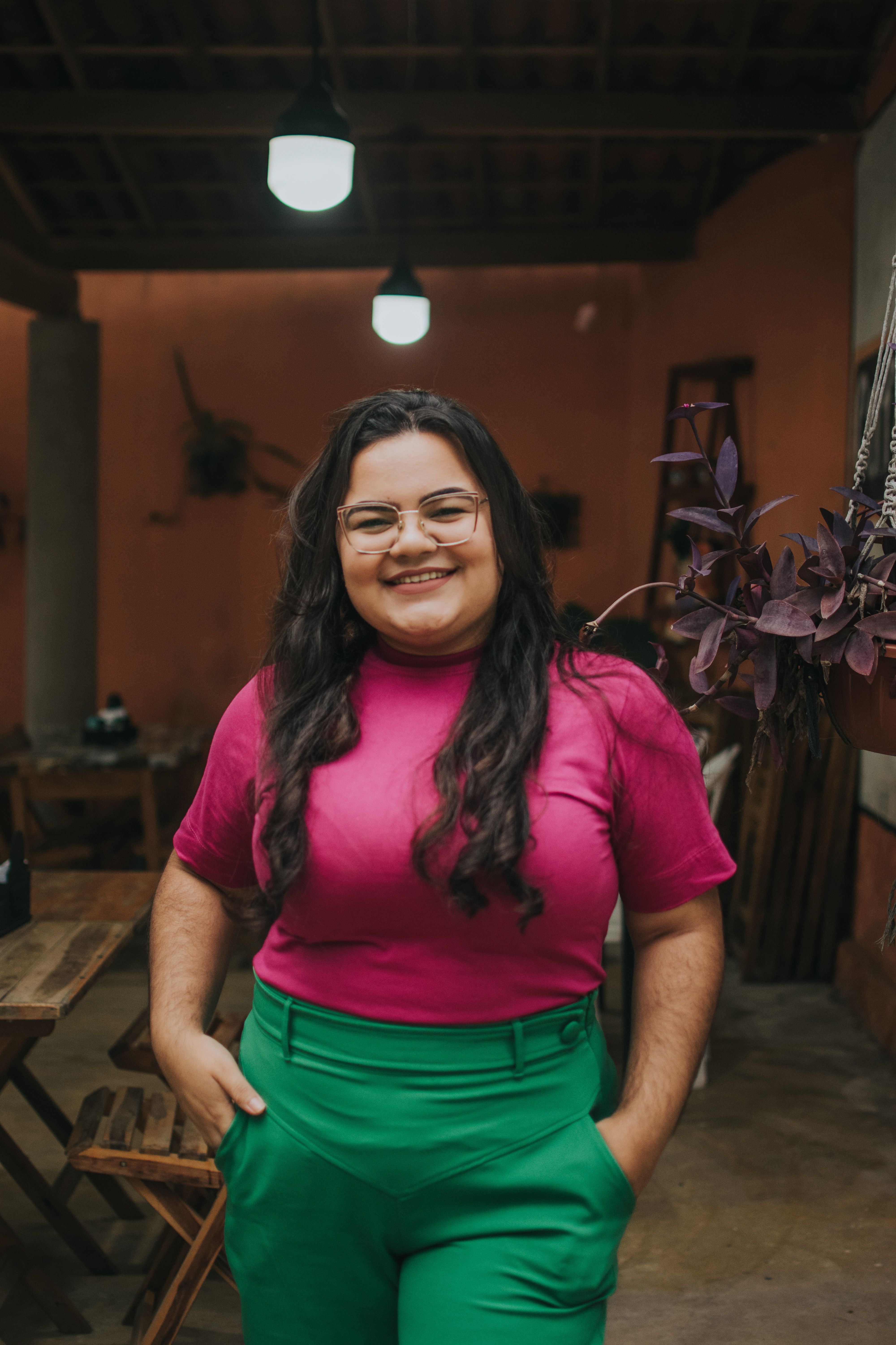 smiling-woman-standing-indoors-wearing-a-vibrant-pink-and-green-outfit,-exuding- - rebeca-medeiros (pexels)