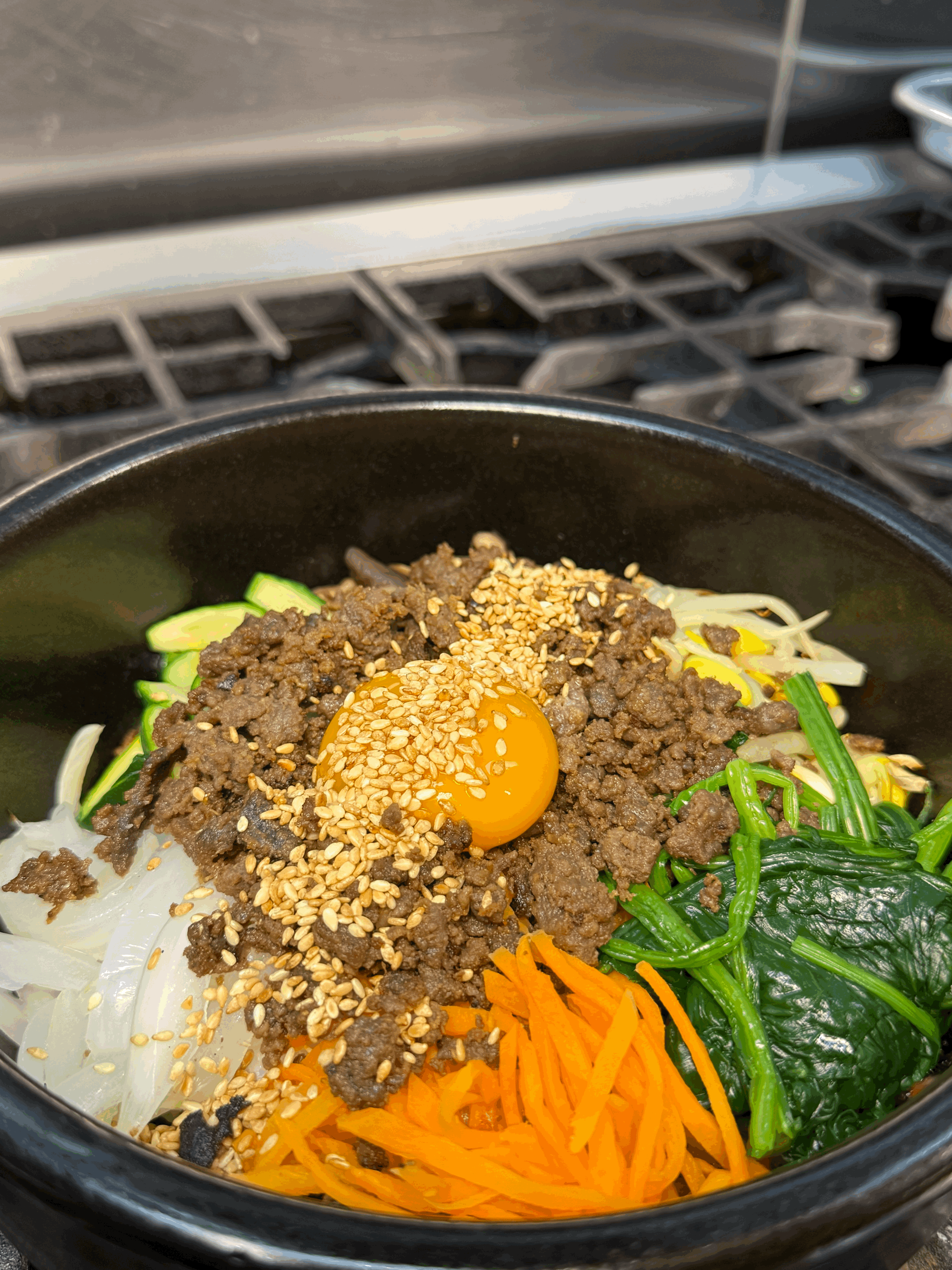 A close-up of a beautifully plated dessert or appetizer on a white table cloth in a dimly lit, elegant restaurant setting, featuring a tall wine glass with white wine.