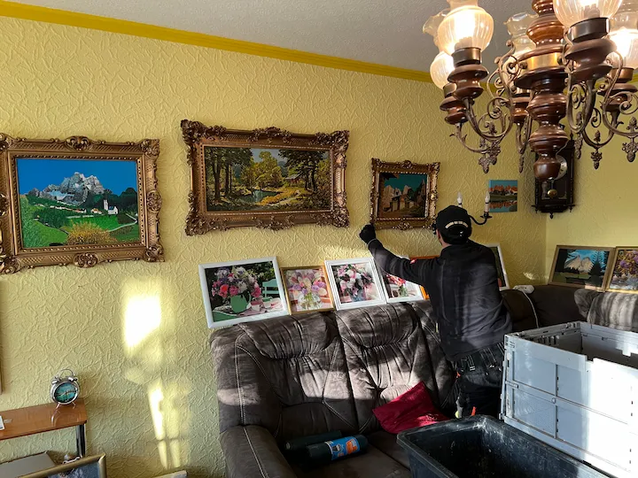Mitarbeiter nimmt gerahmte Bilder von der Wand einer Wohnung ab