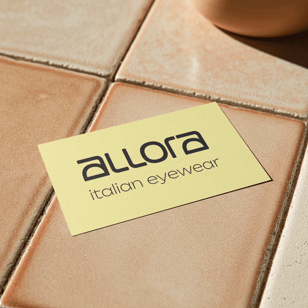 Editorial card mockup showcasing the modern wordmark against warm, textured surfaces.