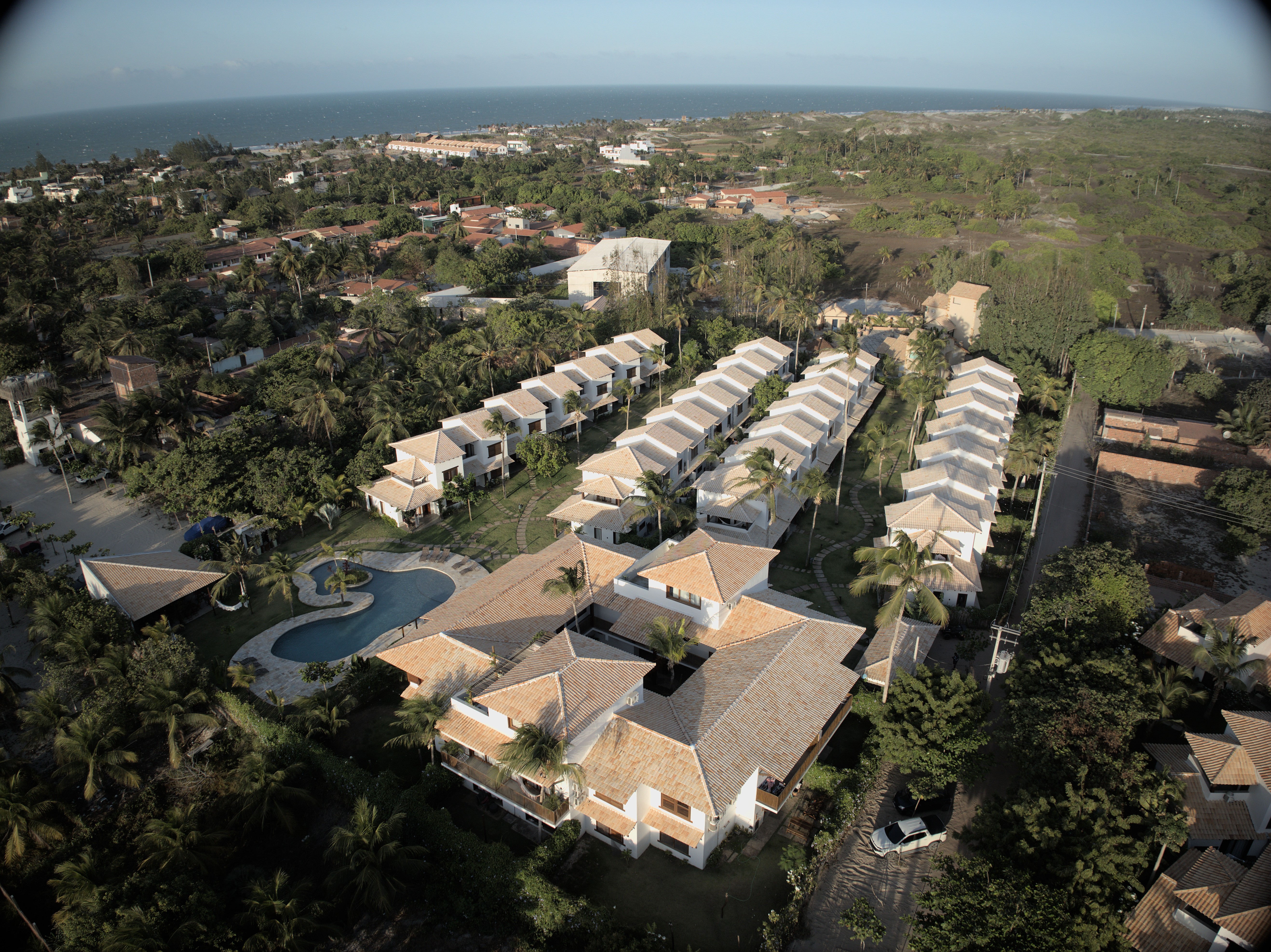 A smiling young man with crossed arms, wearing a plaid shirt and white t-shirt, poses against a dark background.