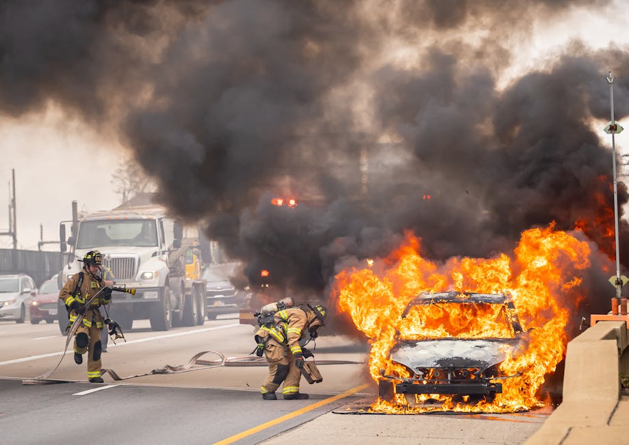Firefighters extinguishing a car fire on a highway.