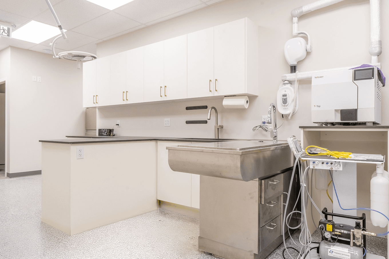 Custom medical workspace with white upper cabinets, integrated sink, and durable countertops in a clinical room.