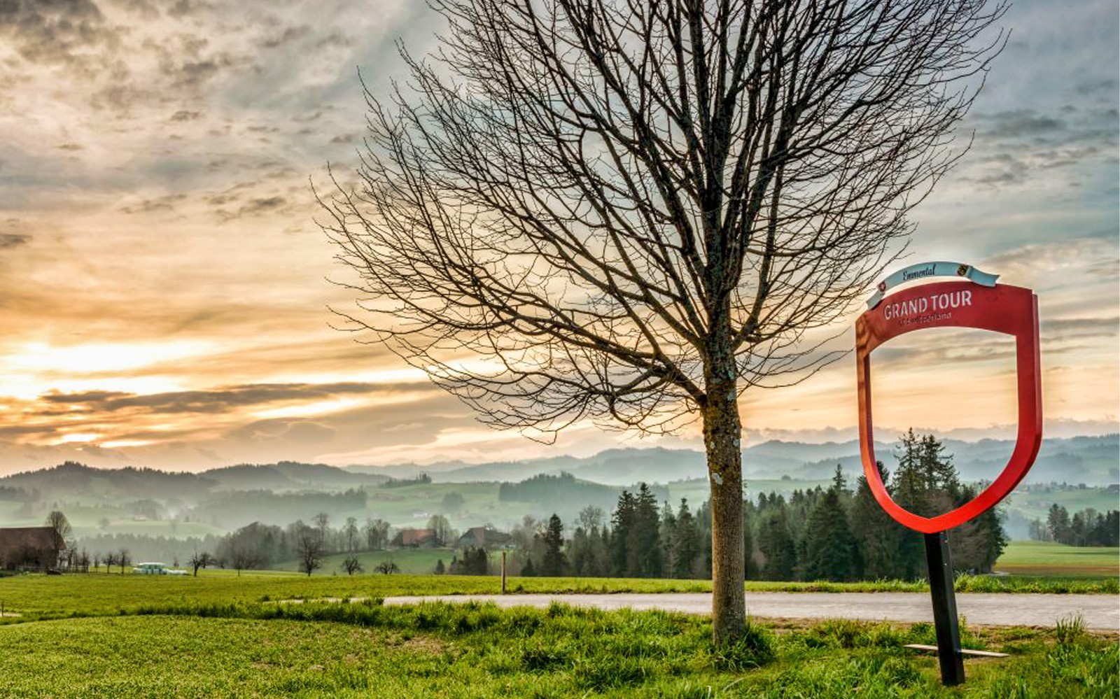 Letrero del Gran Tour y árbol con paisaje de Emmental cerca de Berna, Suiza.