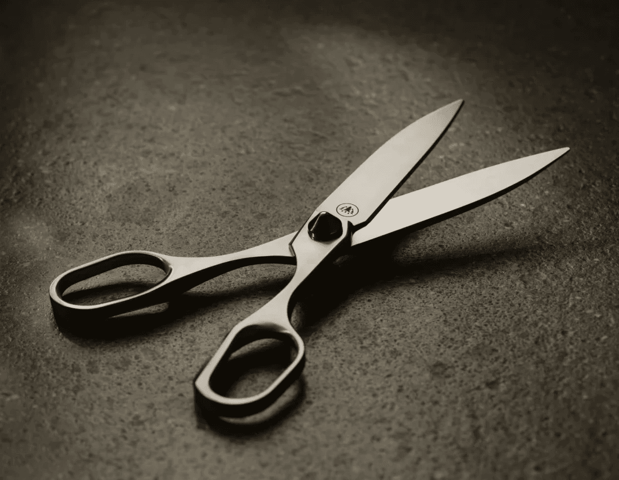 Stainless steel Horl scissors laying on a dark stone countertop in a kitchen with warm, moody ambient lighting.