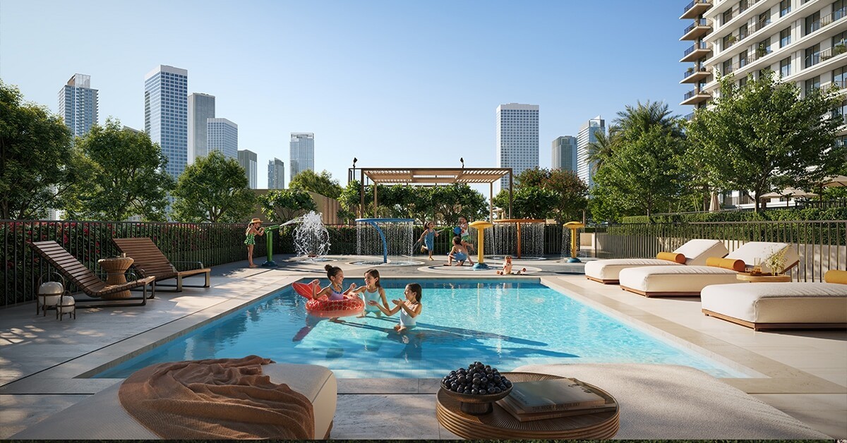 A pool with lounge chairs and a water feature in front of the Creek Haven high-rise building.