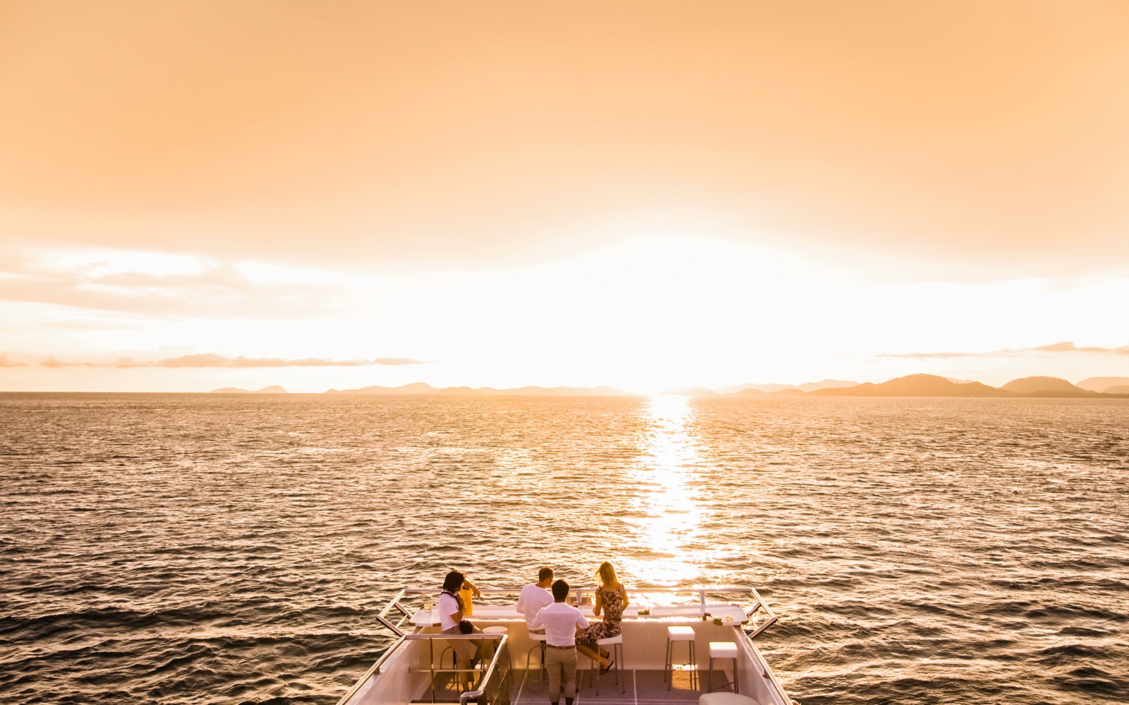 Sunset view from a boat on Split Riviera cruise with people enjoying drinks.