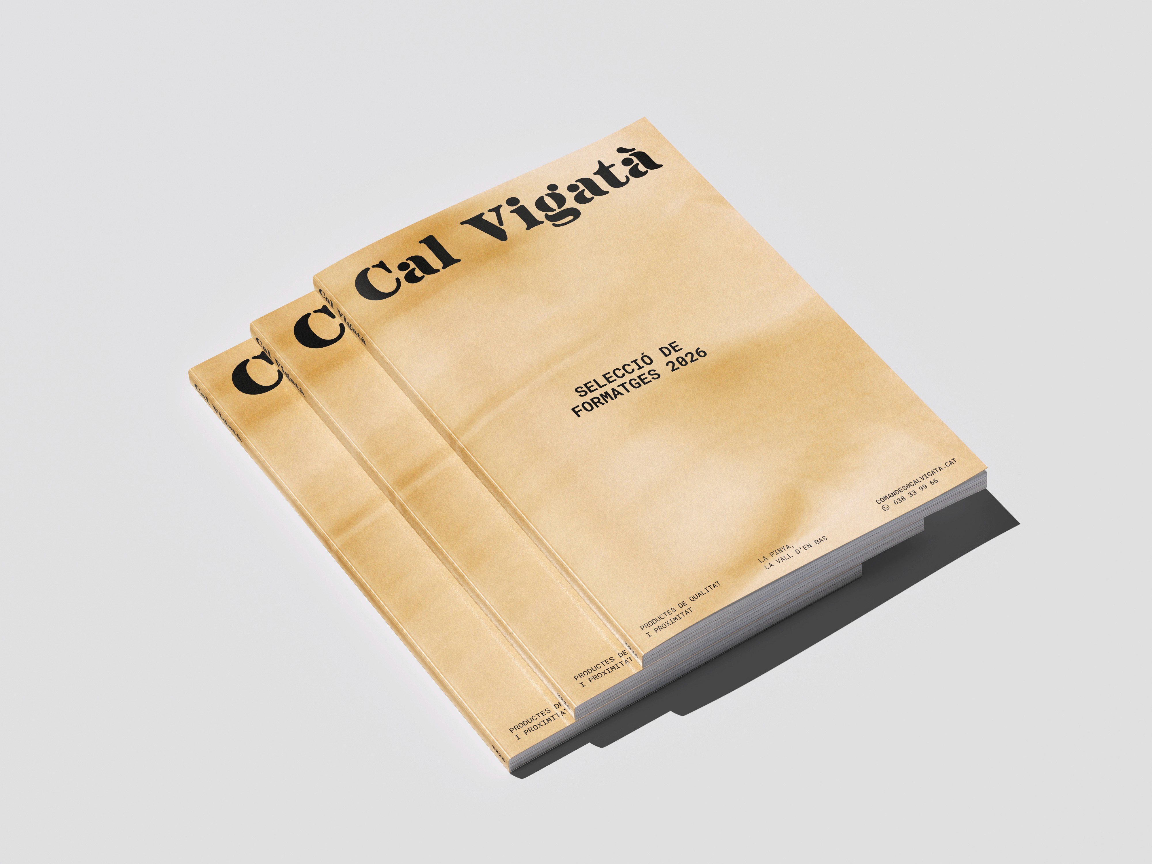 Stack of editorial catalogs for "Cal Vigatà" featuring a minimalist cream-colored cover with bold, black serif typography and clean layouts.