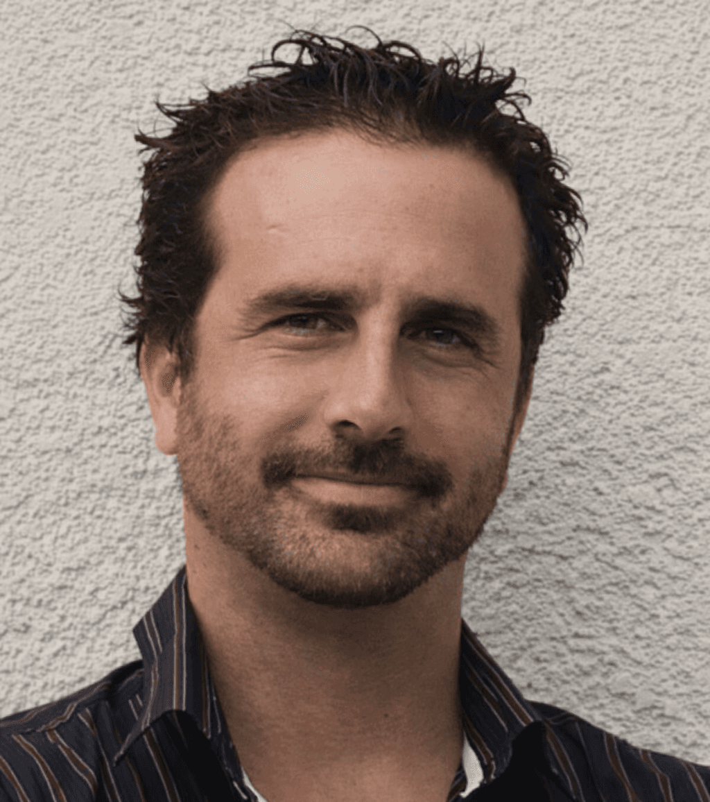 A woman with long hair stands, looking thoughtfully into the distance.