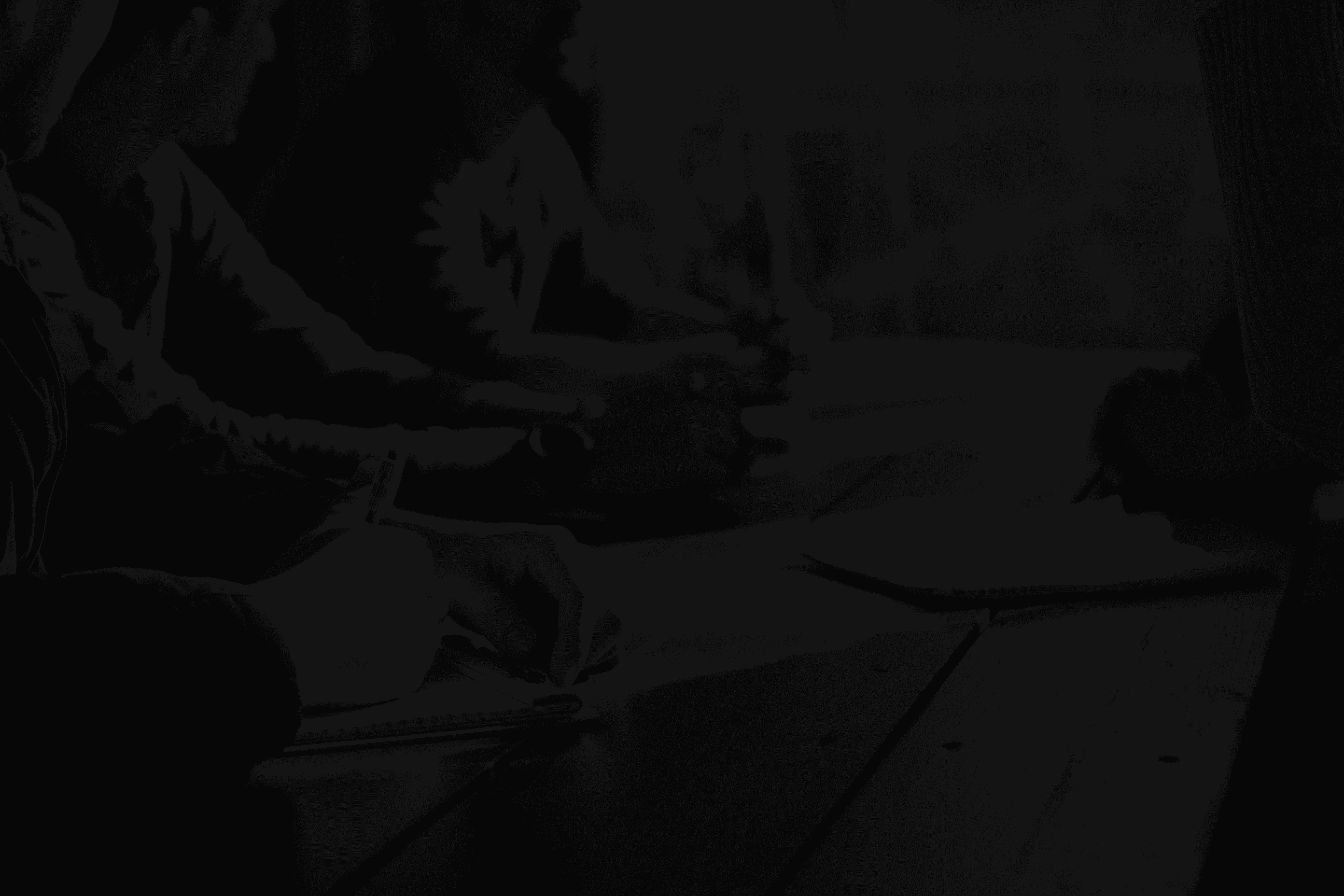 people sitting on chair in front of table while holding pens during daytime