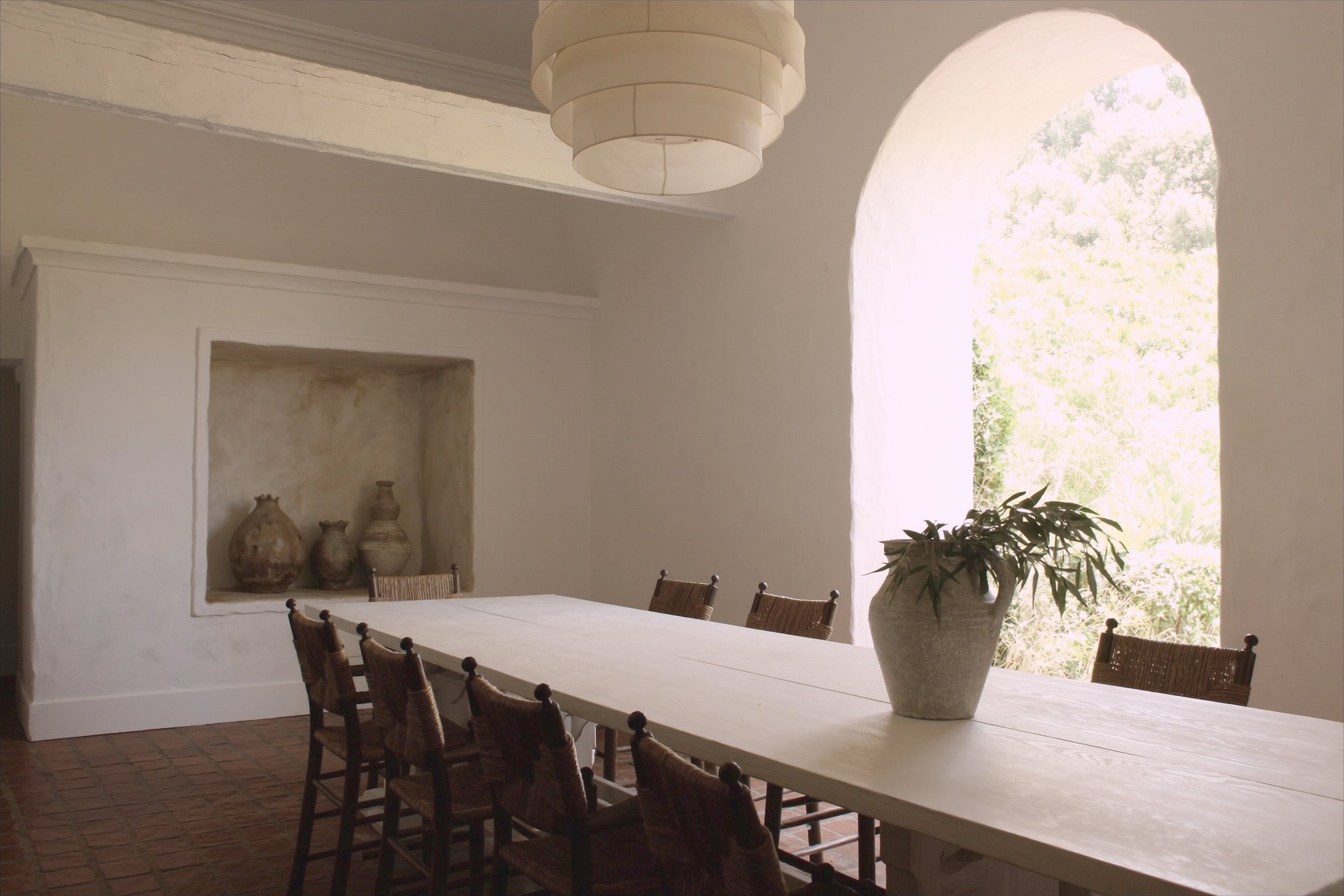 Ojai farmhouse dining room with a long trestle table, rush chairs and an arched opening