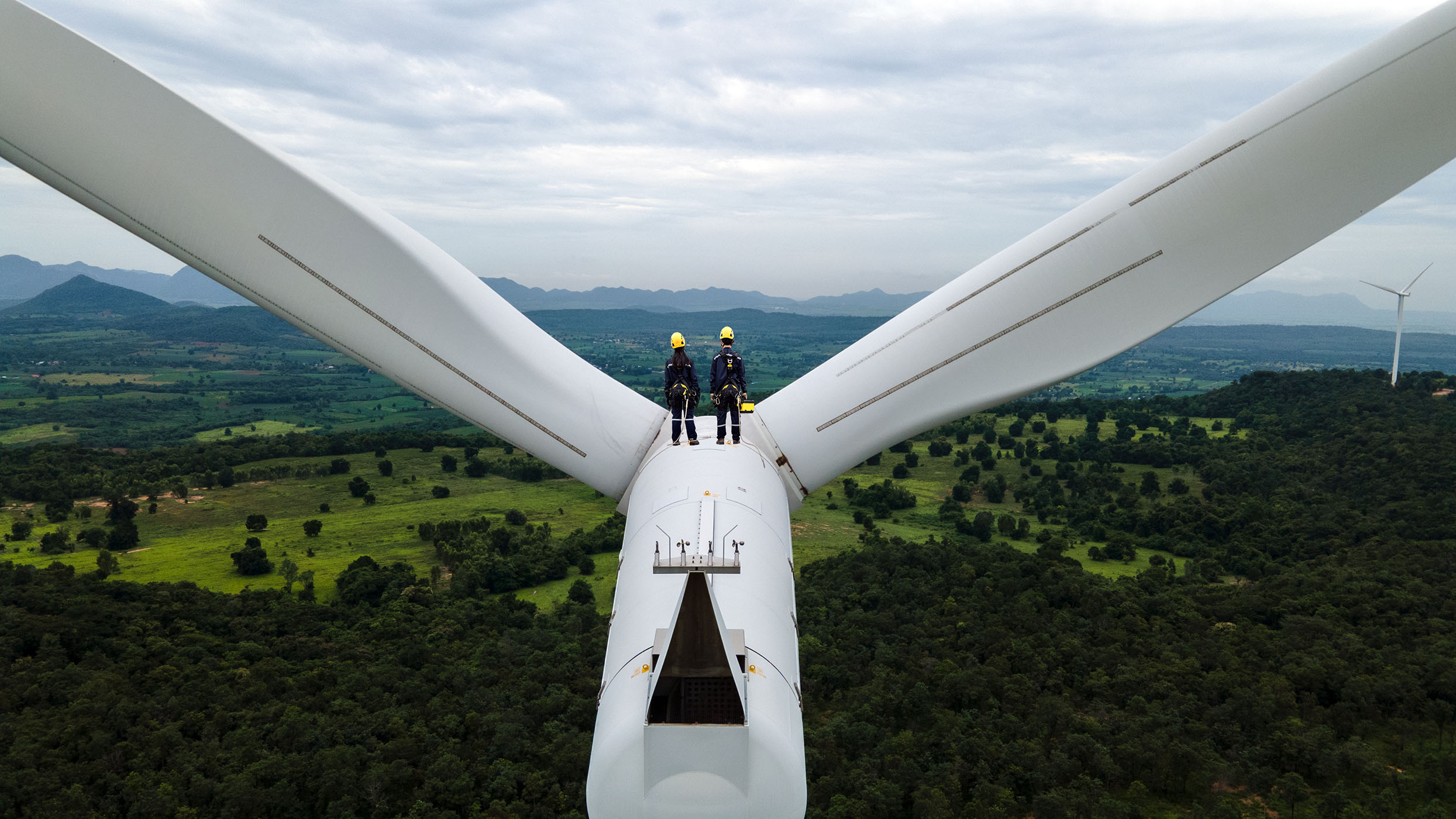Workers standing on top of wind turbine.