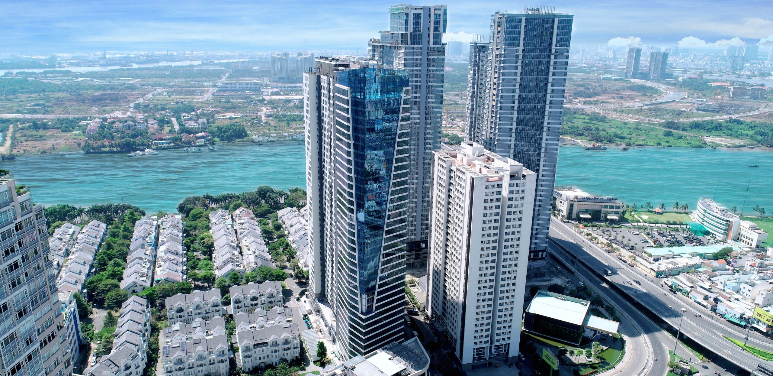 Aerial landscape featuring a modern glass tower near the water, showcasing luxury real estate investment options.