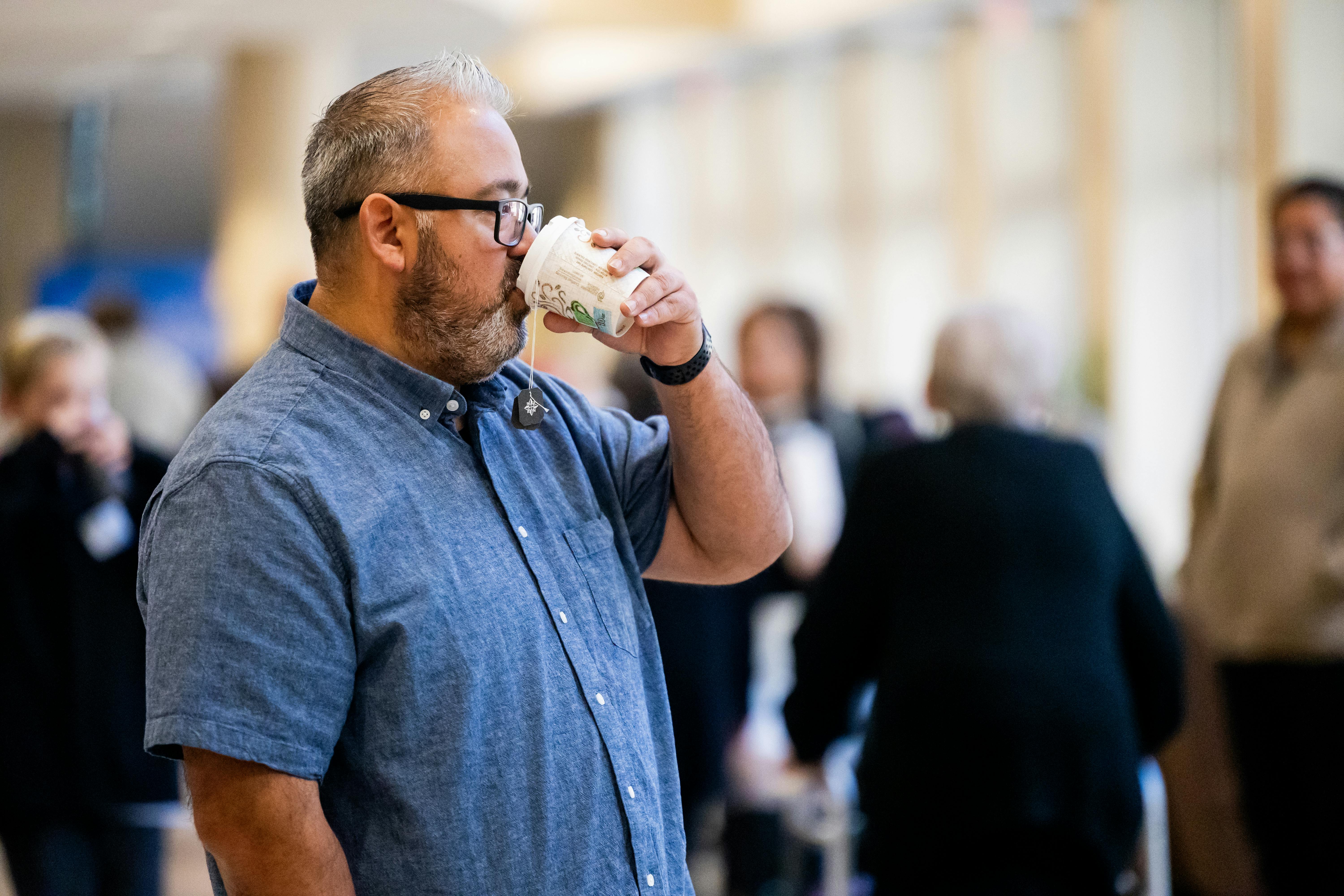 Professionista durante una pausa caffè a un evento, simbolo dei momenti informali in cui nascono relazioni lavorative autentiche.