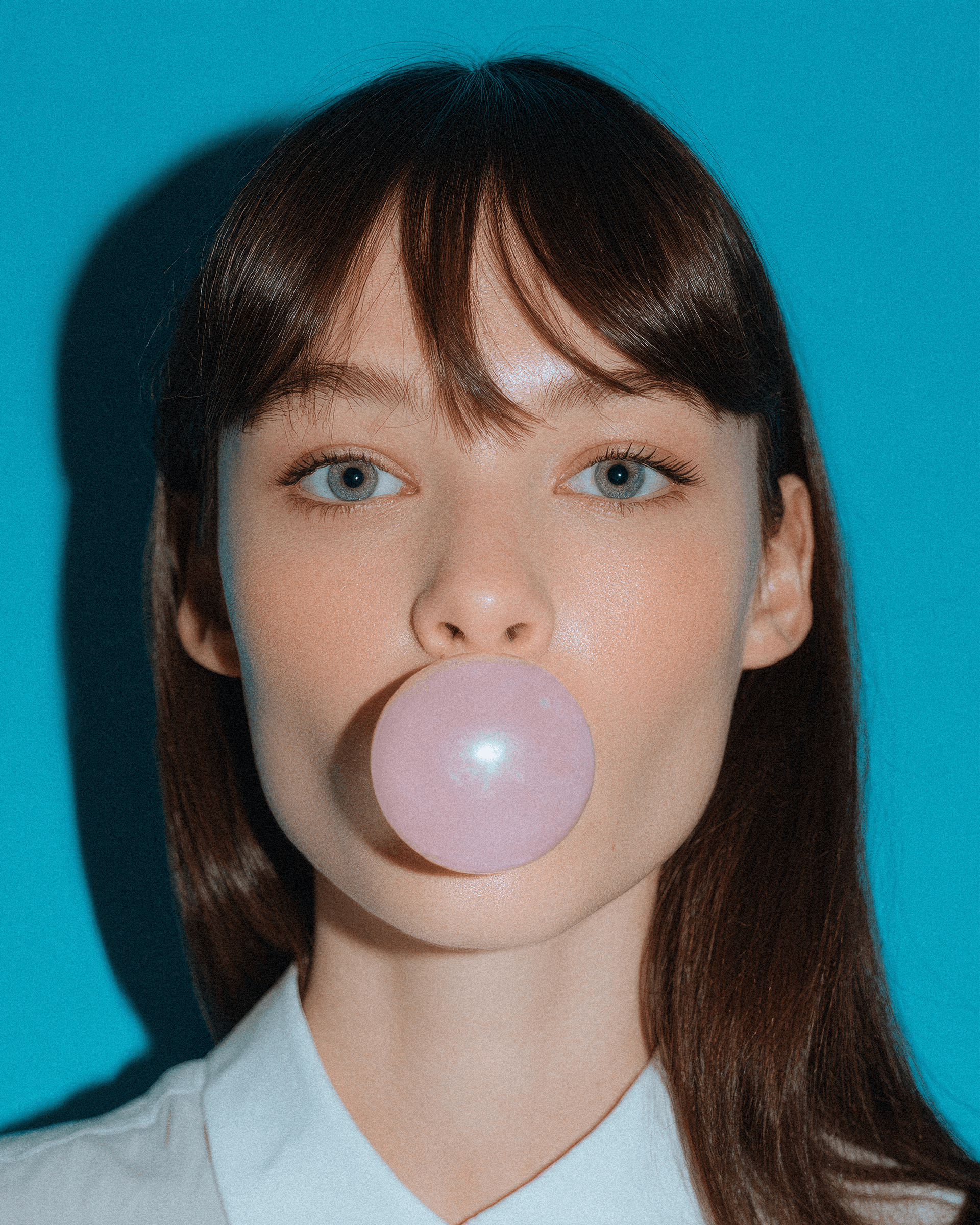 Minimalist facade with red window and striped awning on a white stucco wall under a clear blue sky.