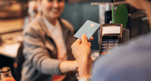 A shopper holding their credit card to a card reader in a store.