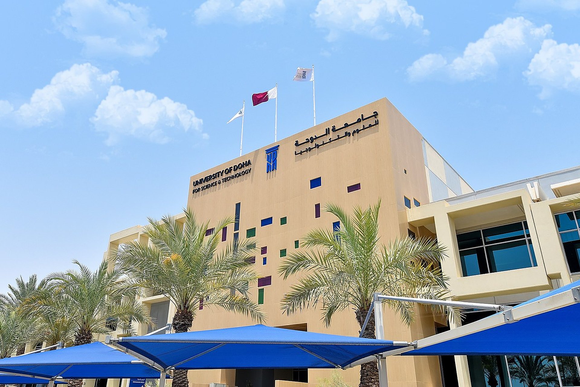 Le campus de l'Université de Doha pour les sciences et la technologie, l'UDST, à Doha, avec le nom de l'université sur la façade et les drapeaux du Qatar