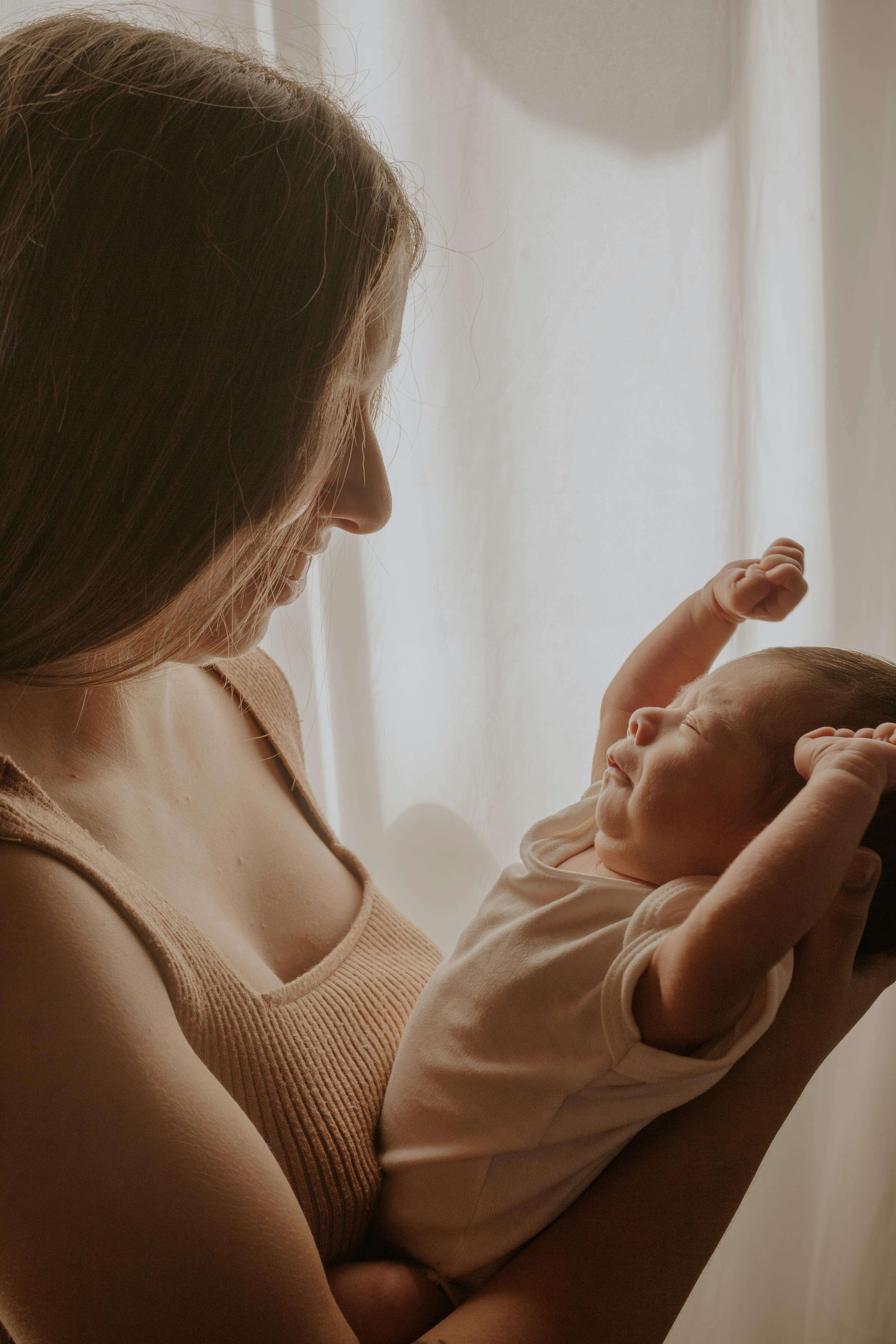 Warm maternity care illustration, mother holding newborn, soft gradient background, non-graphic, clean typography space.