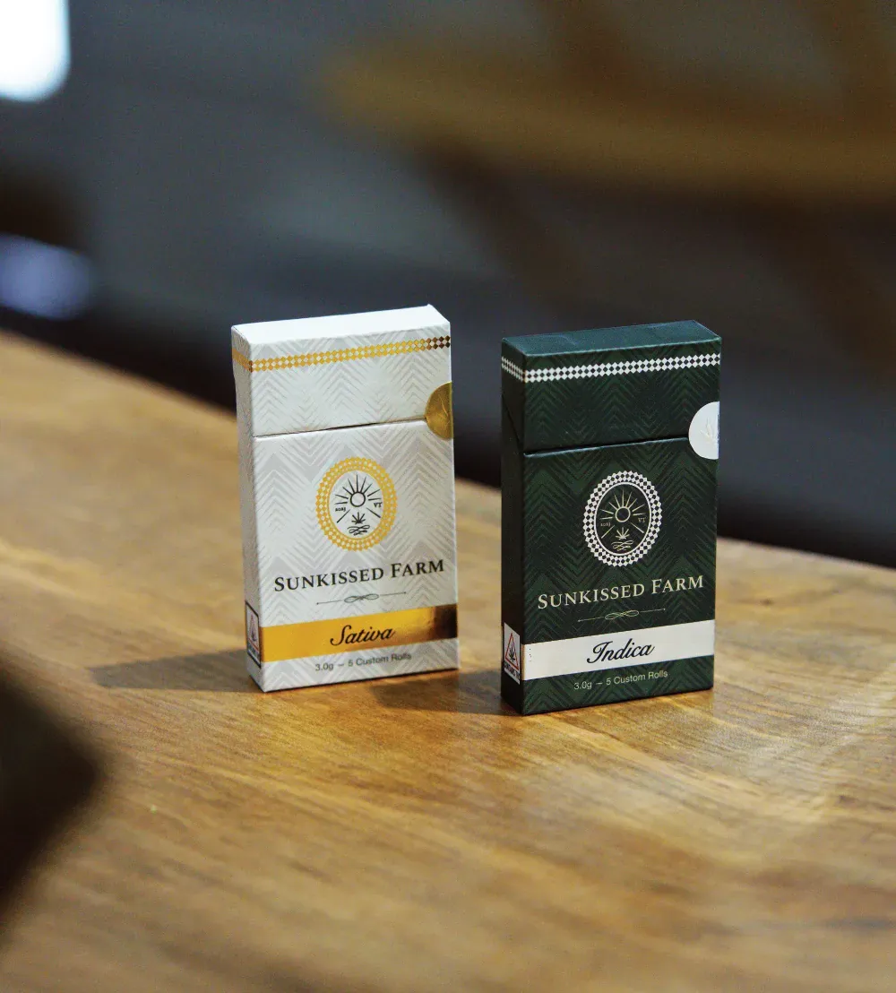 Sunkissed Farm sativa and indica pre-roll packs side by side on a wooden surface, available at Vermont cannabis dispensaries