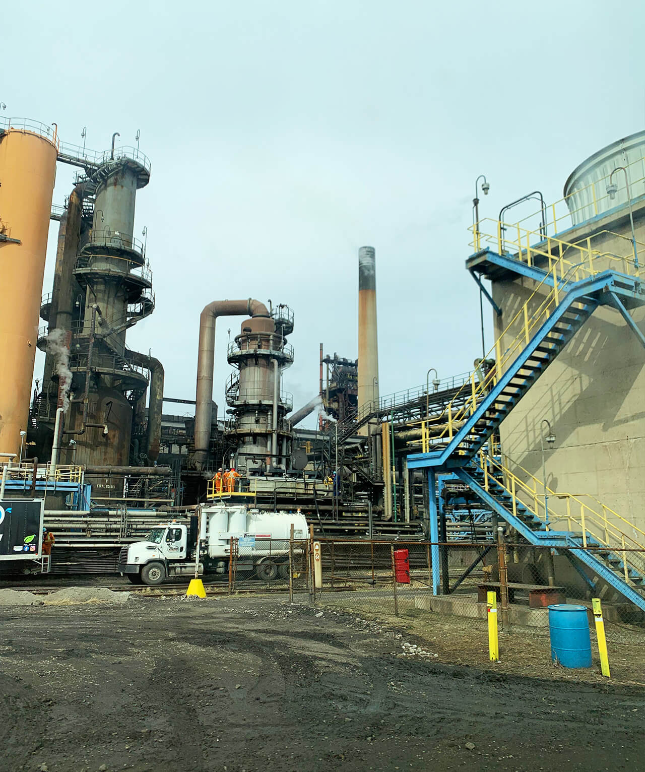 A sprawling industrial plant with multiple pipes and a truck parked nearby.