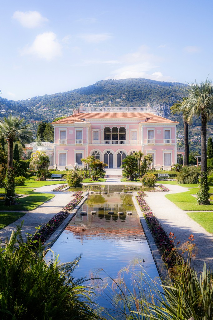 a large pink house with a pond in front of it