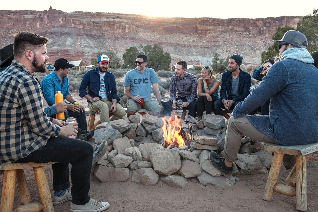 Group of friends enjoying a campfire gathering in a scenic desert location.