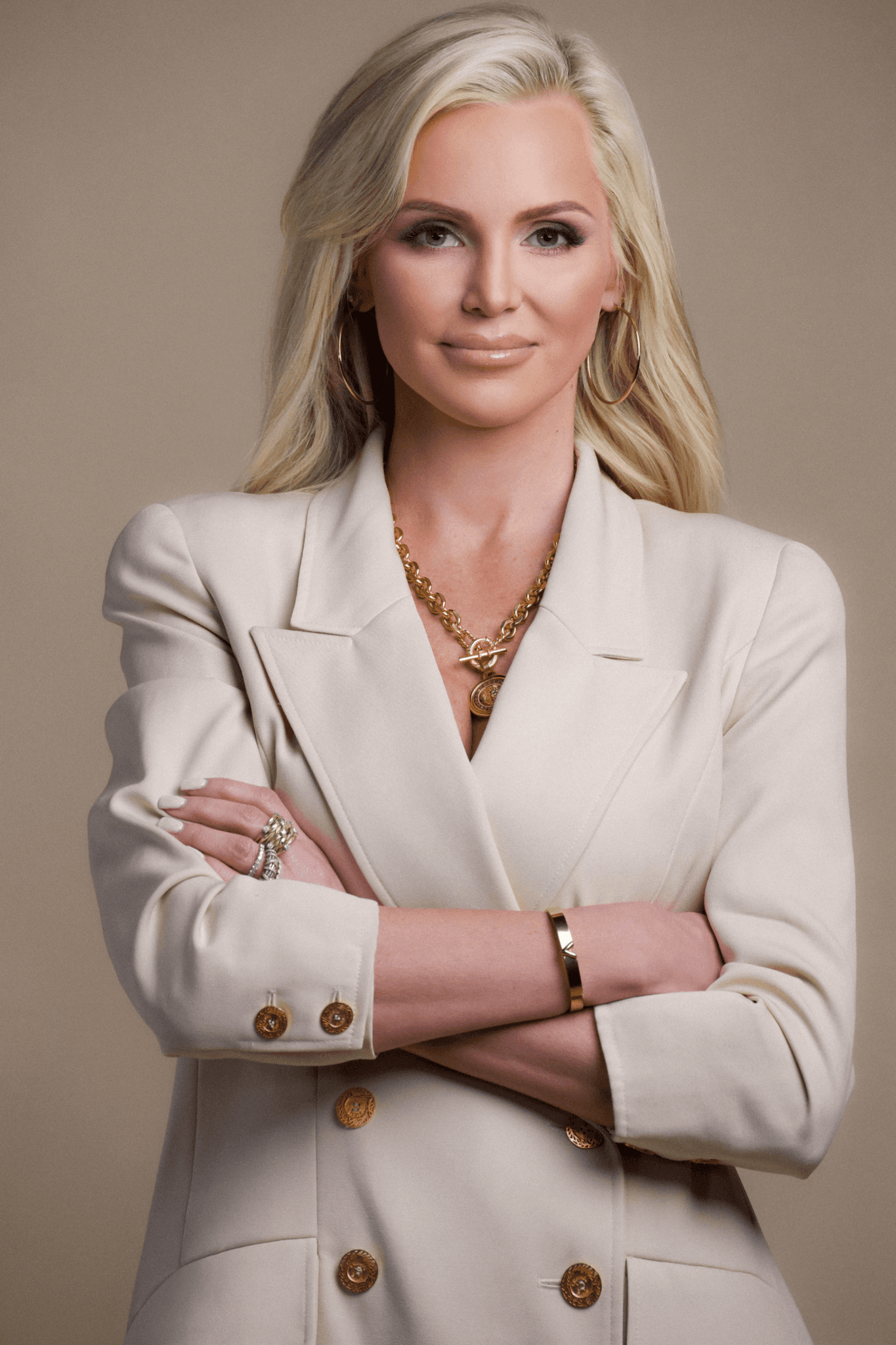 Bethany Schneider standing with arms crossed in a cream blazer.