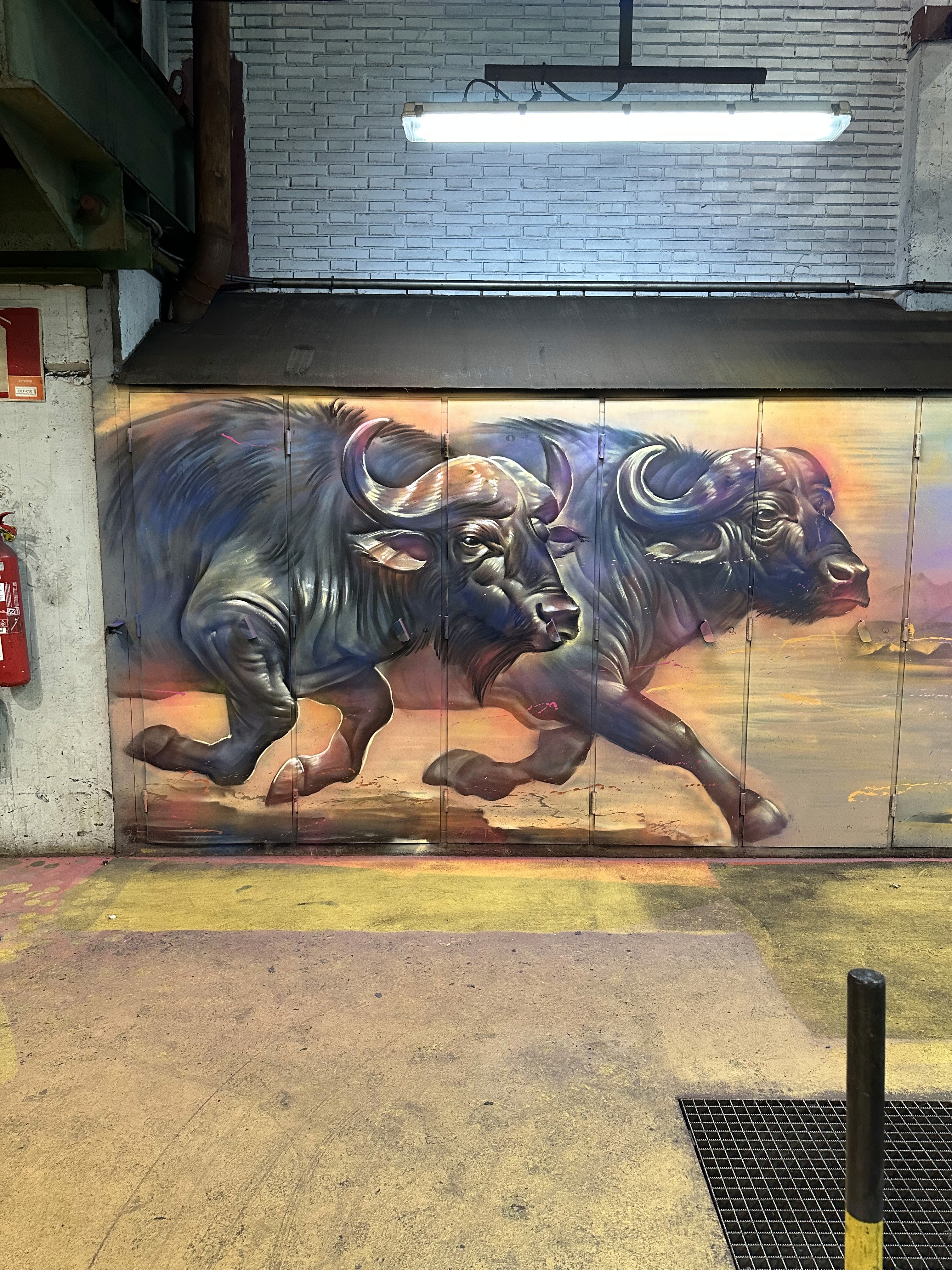 Mural de búfalos pintado sobre puertas metálicas en la planta de ArcelorMittal en Avilés