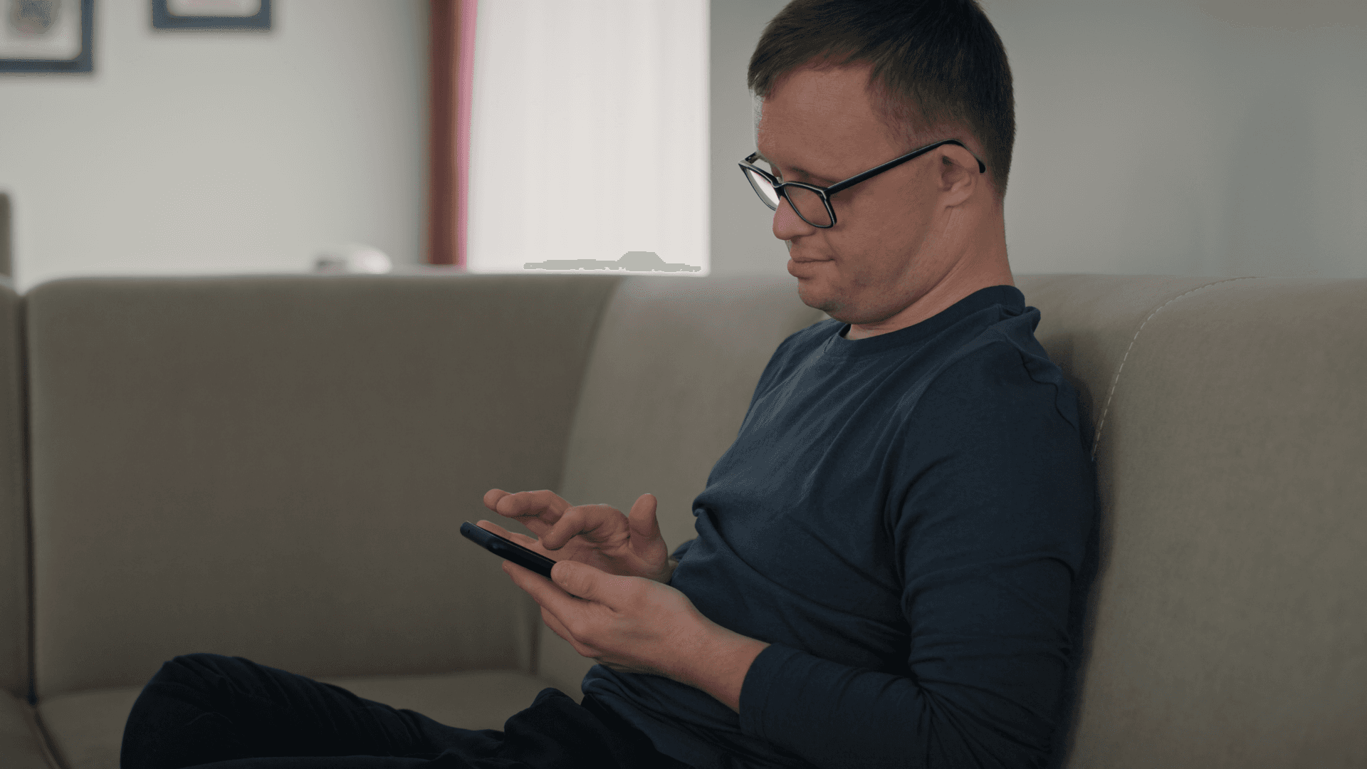 Man sitting on the couch using his phone.