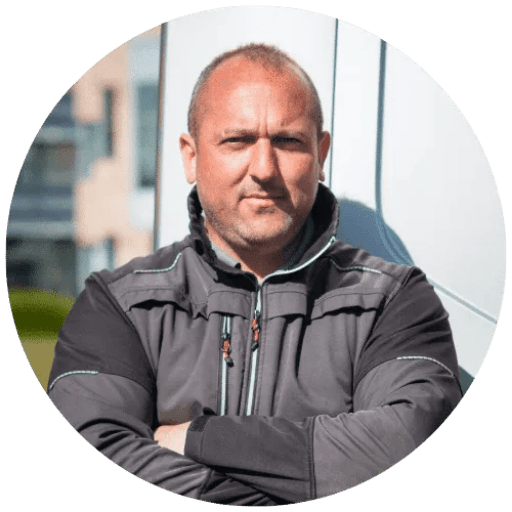 A person on a white shirt and black coat standing at the window indoor of the office