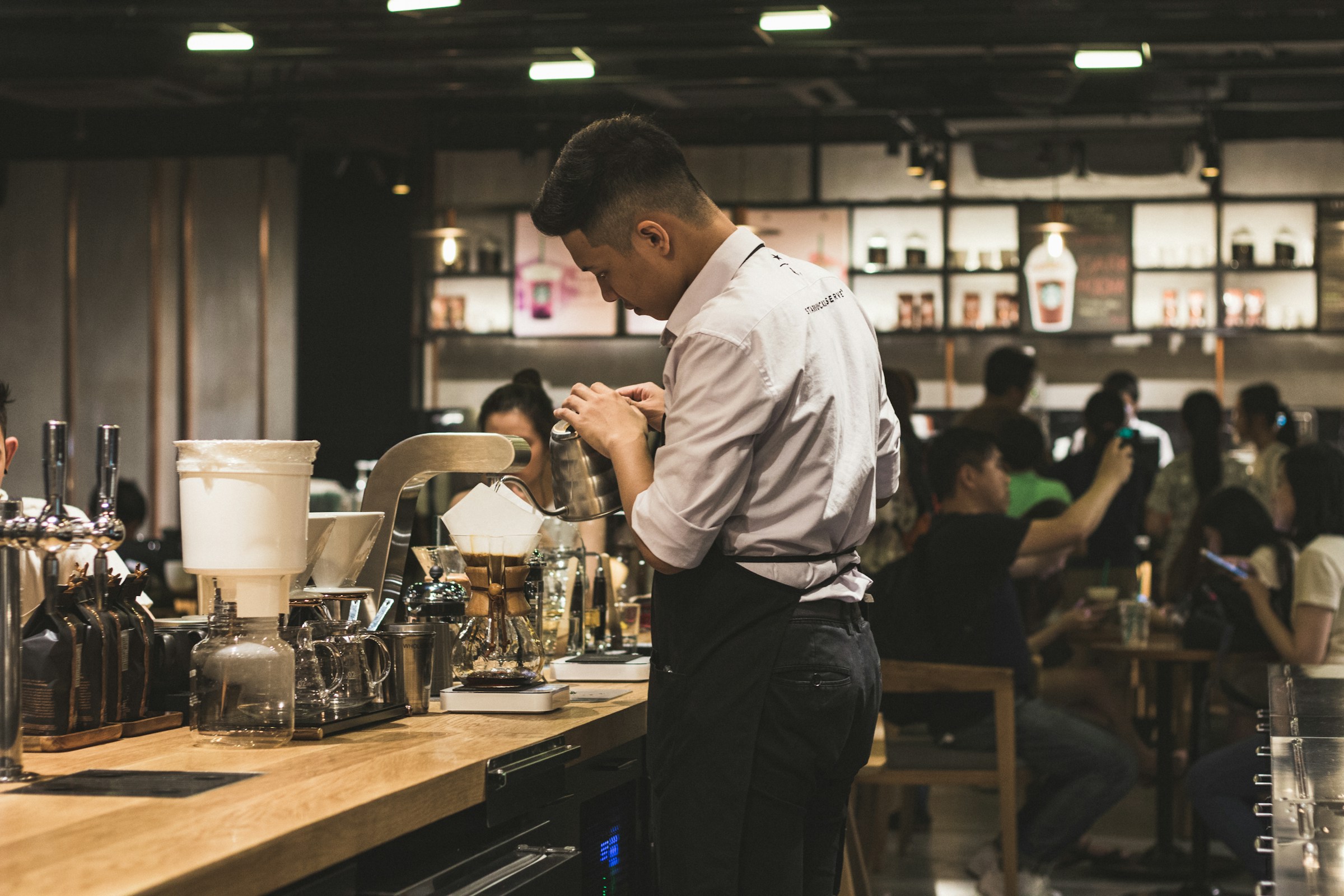A bartender stands behind the counter, ready to serve drinks in a cozy cafe.
