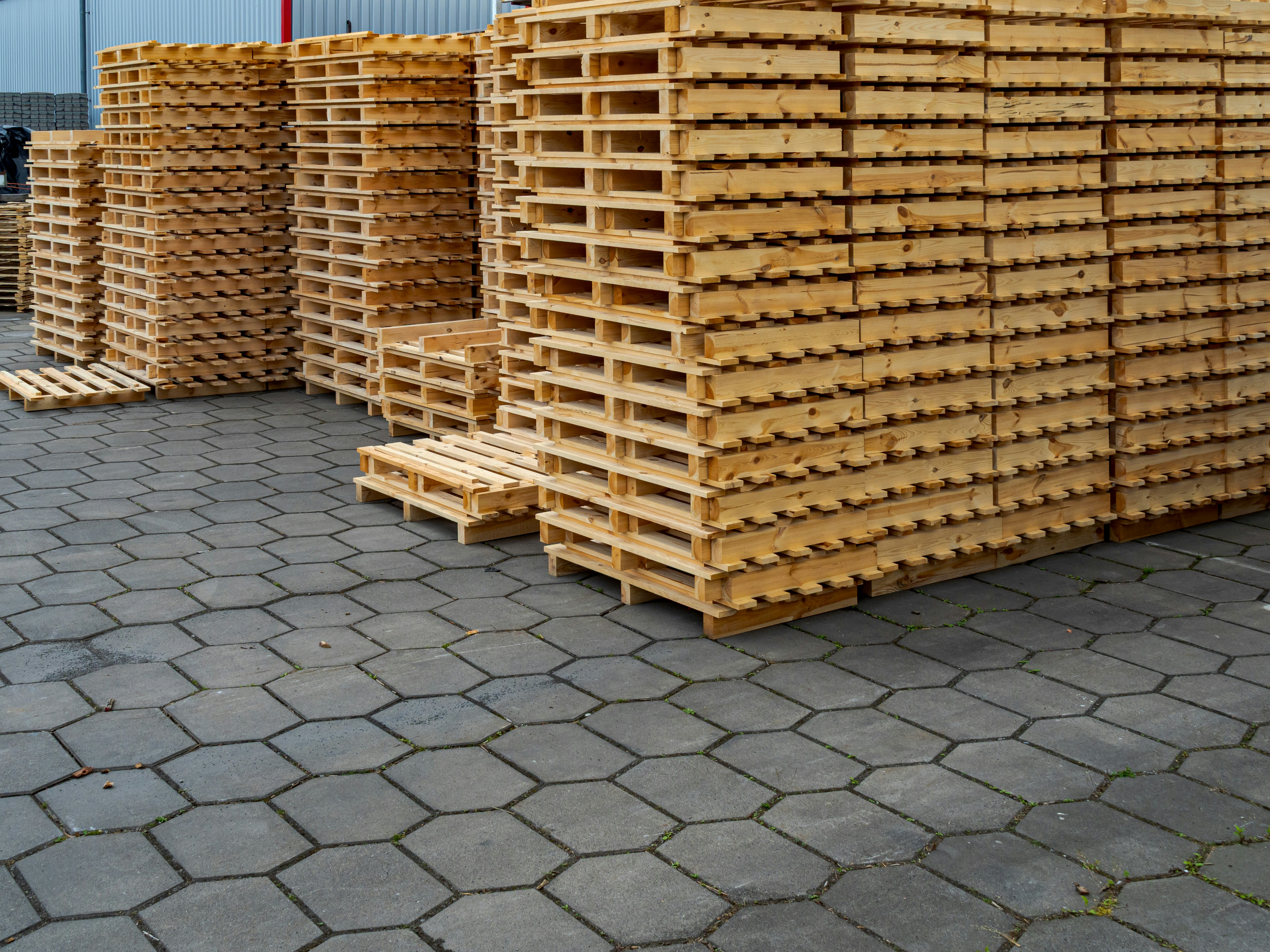 Stacks of wooden pallets on a paved surface.
