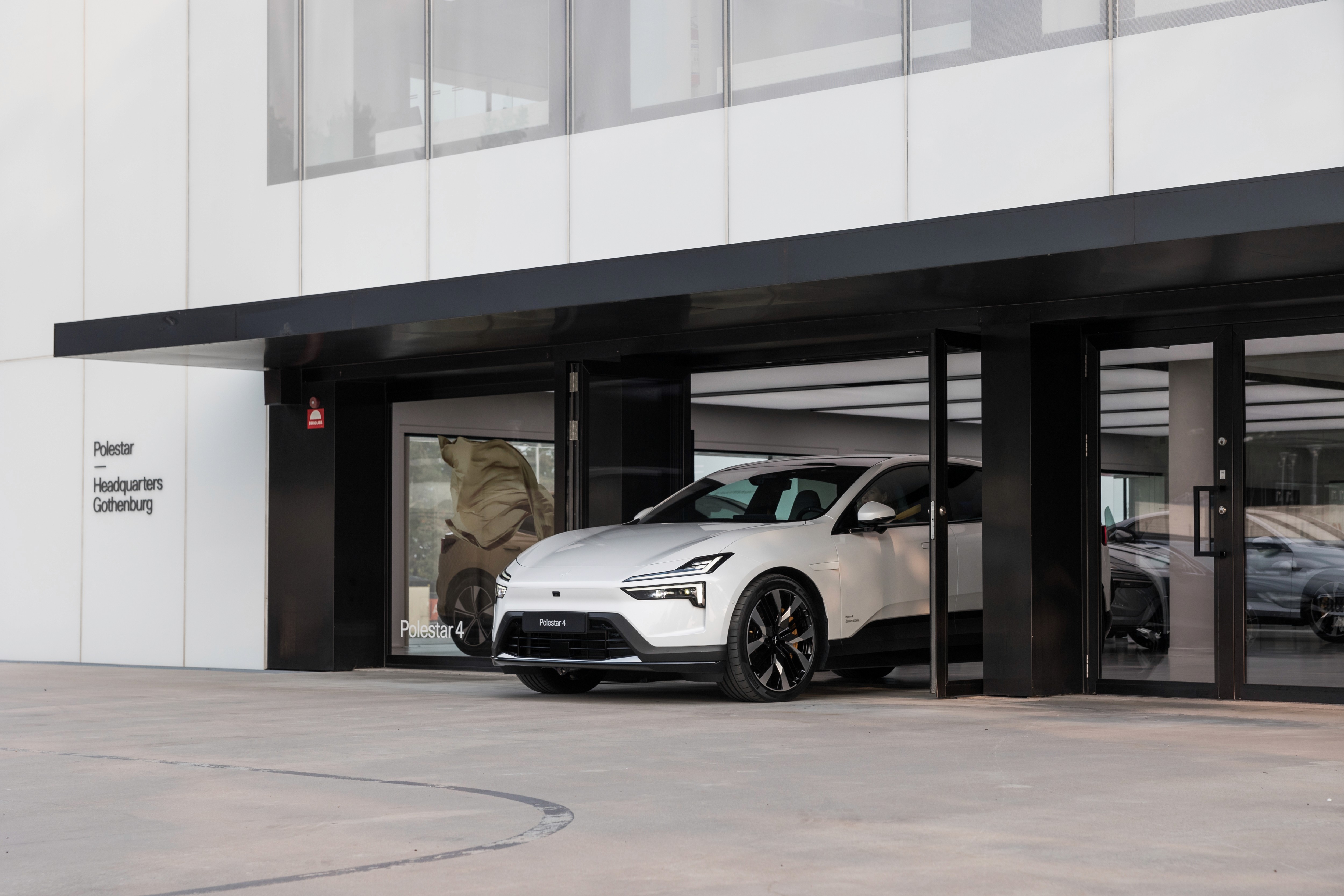 Polestar 4 blanche devant le siège de Polestar à Göteborg, SUV coupé électrique dans un cadre institutionnel