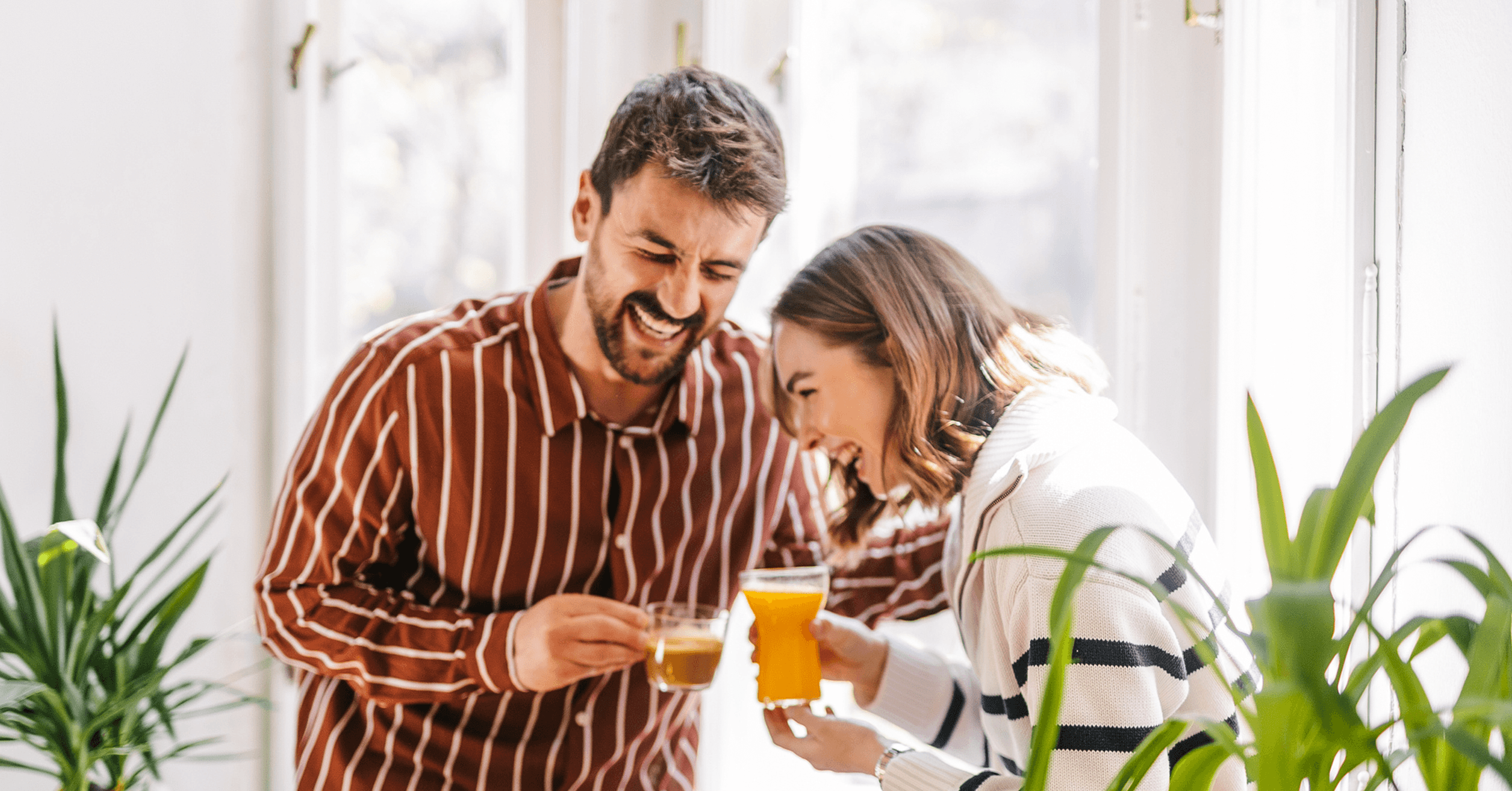 En man och en kvinna står och skrattar och njuter av varandras sällskap med te i handen.