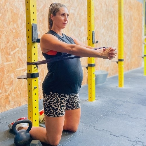 Femme enceinte réalisant un exercice de renforcement musculaire avec un élastique adapté au sport pendant la grossesse