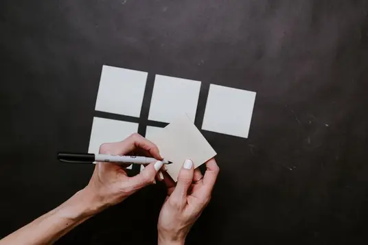 Close-up of a person writing on sticky notes for organizing presentation ideas.
