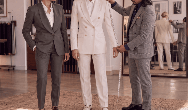 Queer couple having their bespoke wedding suits adjusted during a final tailor fitting