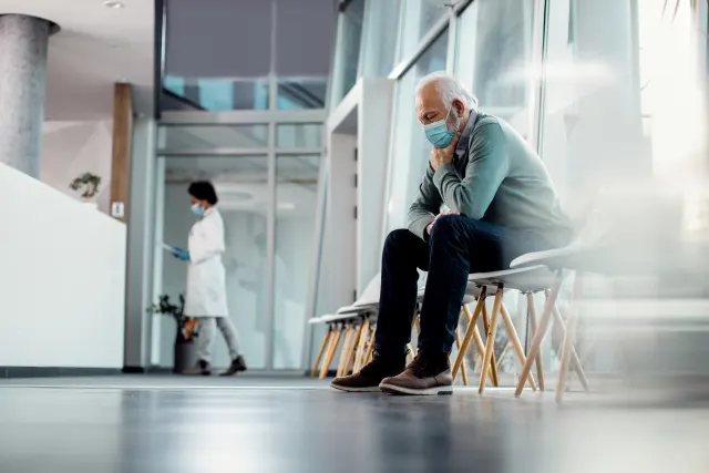 Hombre mayor esperando en la sala de un centro sanitario, reflejo de las listas de espera que llevan a contratar un seguro de salud privado a partir de los 65 años.