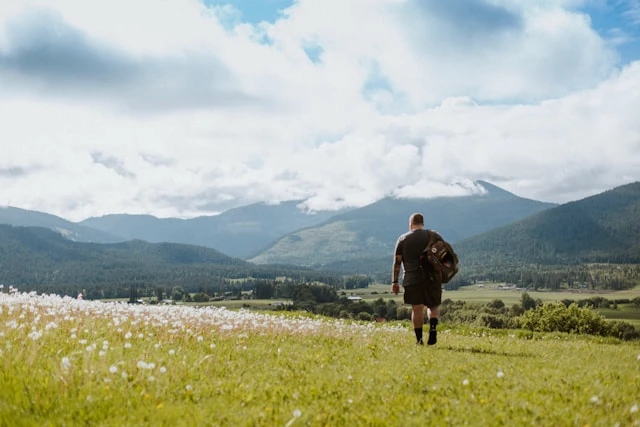 Person standing in an open landscape with mountains in the distance