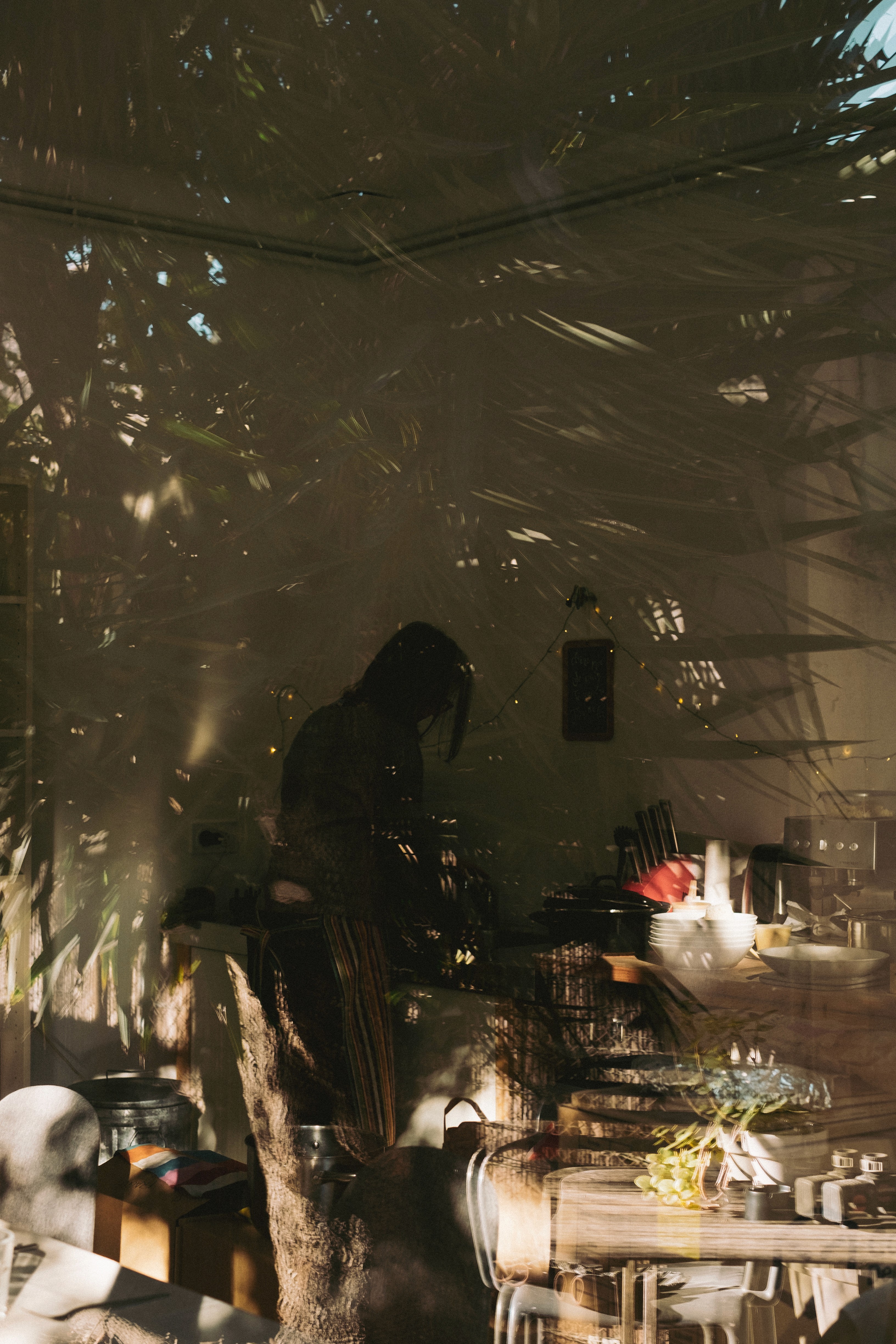 A window reflection shows a person cooking