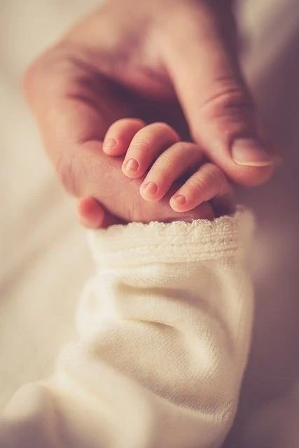 Tiny baby fingers holding an adult finger
