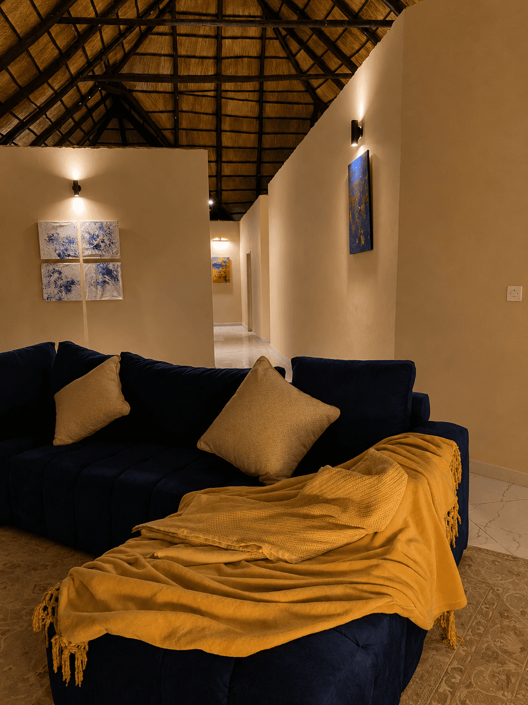 Navy sofa with warm throw beneath a thatched roof