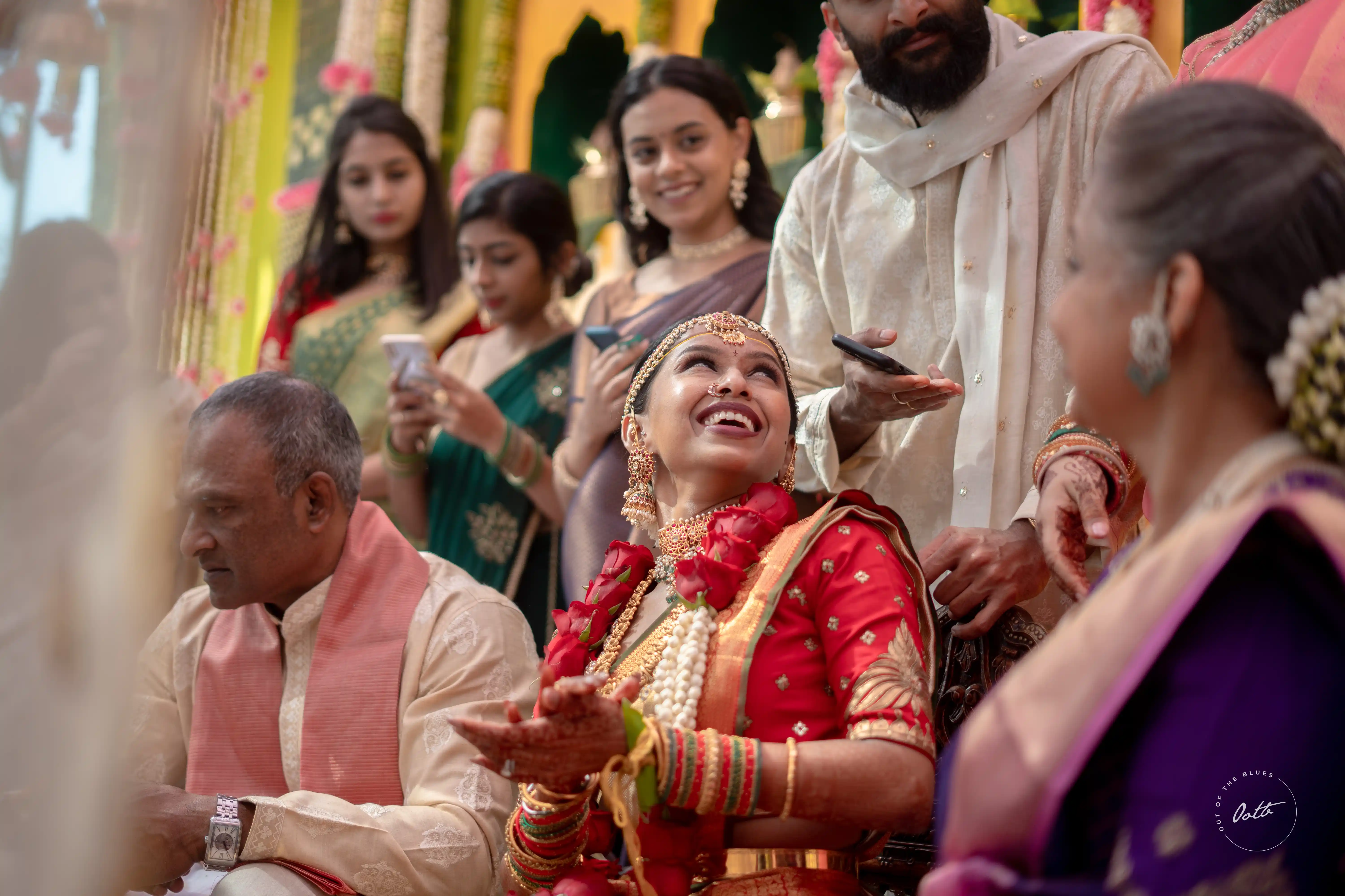 Natural, candid shot of the bride in traditional dress, radiating joy as she celebrates with family, a beautiful moment by Out of The Blues Fine Art Wedding Photography in Hyderabad.