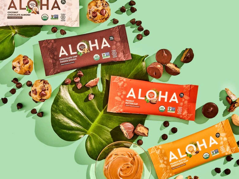 4 aloha bars in packaging with leaves and chocolate treats behind them